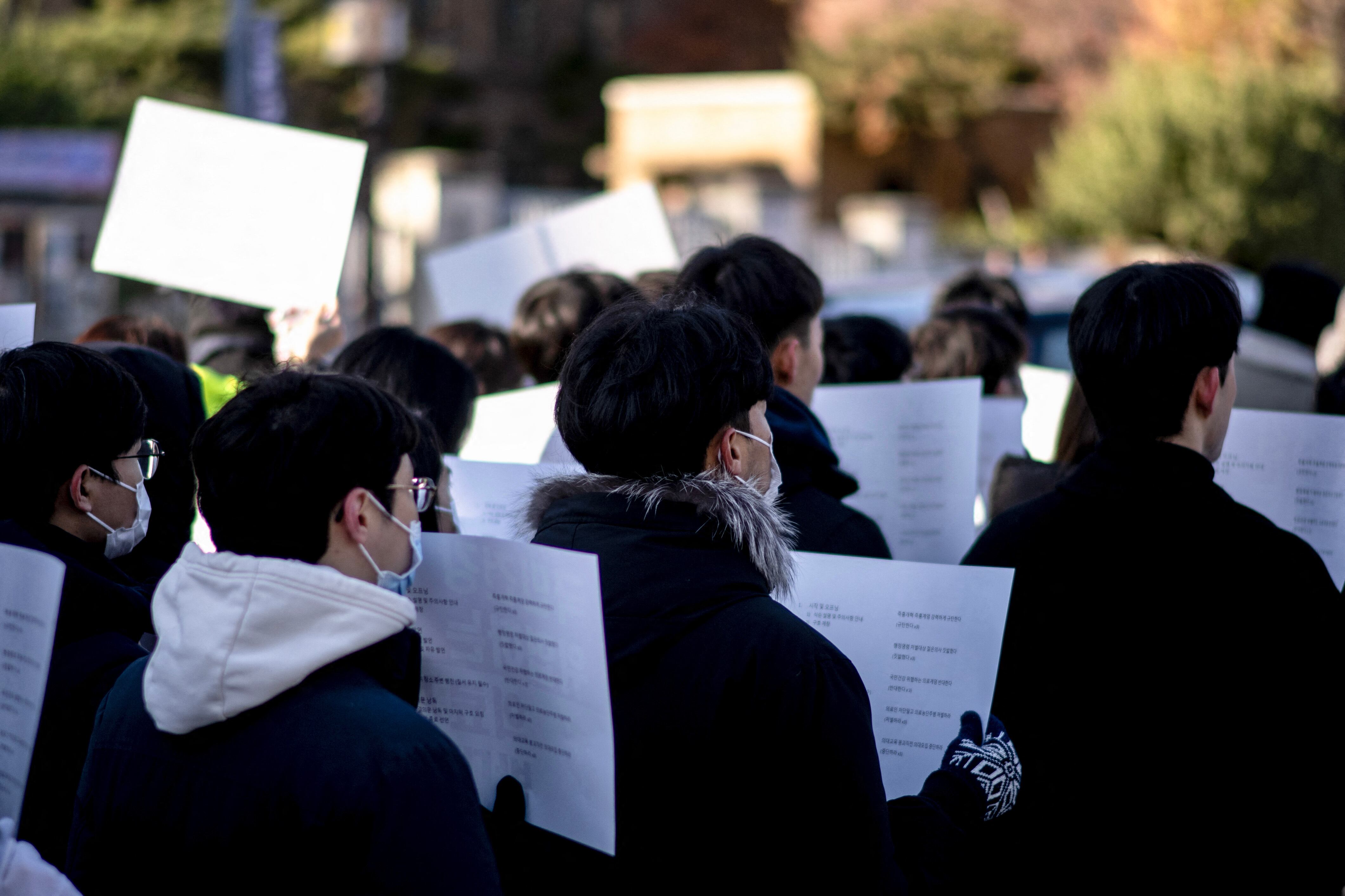 Un grupo de médicos en formación y participantes sostienen carteles durante una manifestación de protesta contra el presidente Yoon Suk Yeol en Seúl.