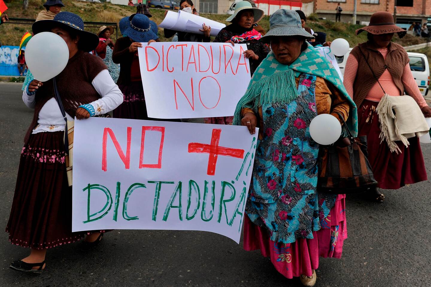 Indigenous opponents to Bolivian President Evo Morales march against the results of Sunday's election with a sign reading "No more dictatorship" in El Alto, Bolivia on October 24, 2019. - Bolivian President Evo Morales declared victory Thursday in elections whose disputed results have triggered riots, a general strike and opposition charges that he is trying to steal the election to secure a fourth straight term. (Photo by JORGE BERNAL / AFP)