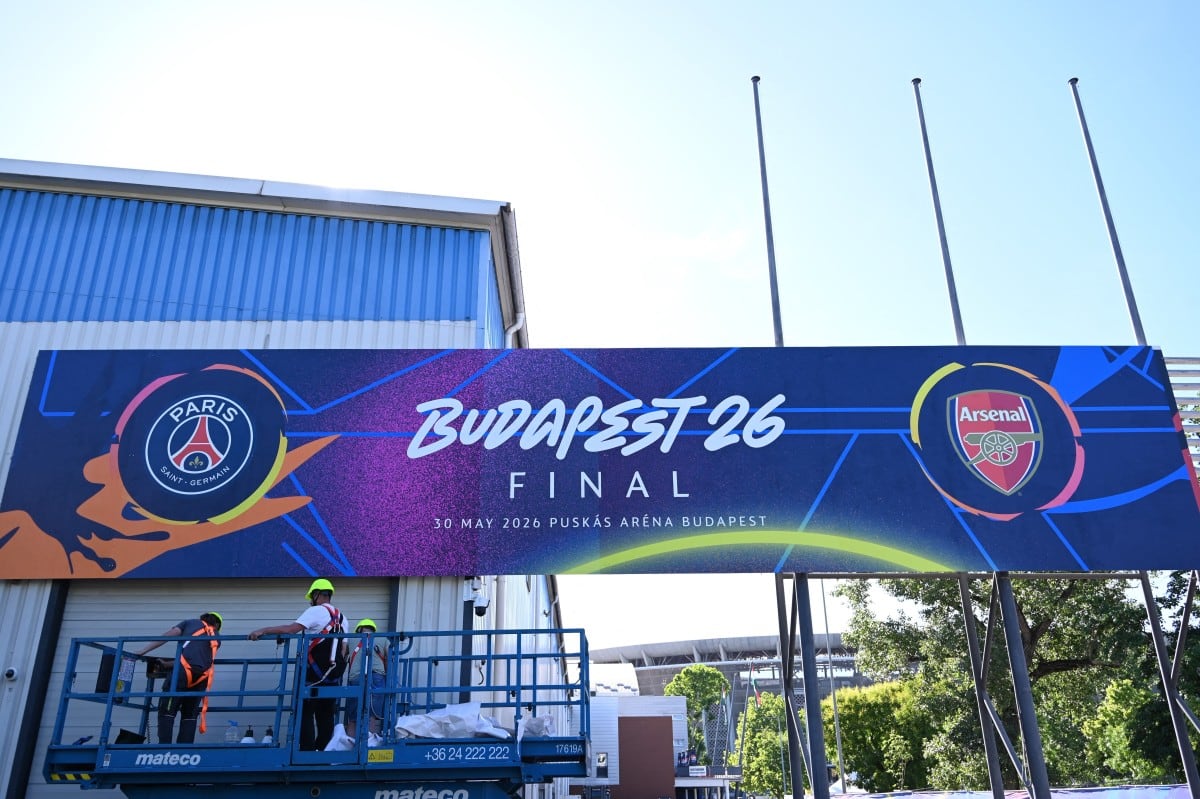 Workers put up a giant UEFA Champions League final poster at the Puskas Arena on May 28, 2026 ahead of the UEFA Champions League in Budapest on May 28, 2026. The stadium, named after Hungary's most famous footballer Ferenc Puskas, will host the Champions League final between Paris Saint-Germain (PSG) and Arsenal on May 30, 2026. (Photo by Attila KISBENEDEK / AFP)