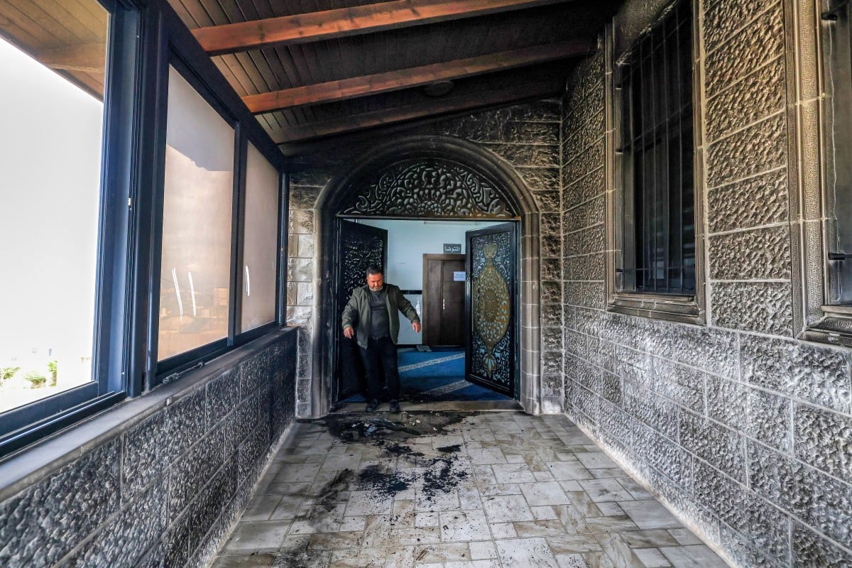 Un hombre inspecciona la entrada calcinada de la mezquita Abu Bakr al-Siddiq, en la aldea de Tell, al oeste de Nablus, en la Cisjordania ocupada.