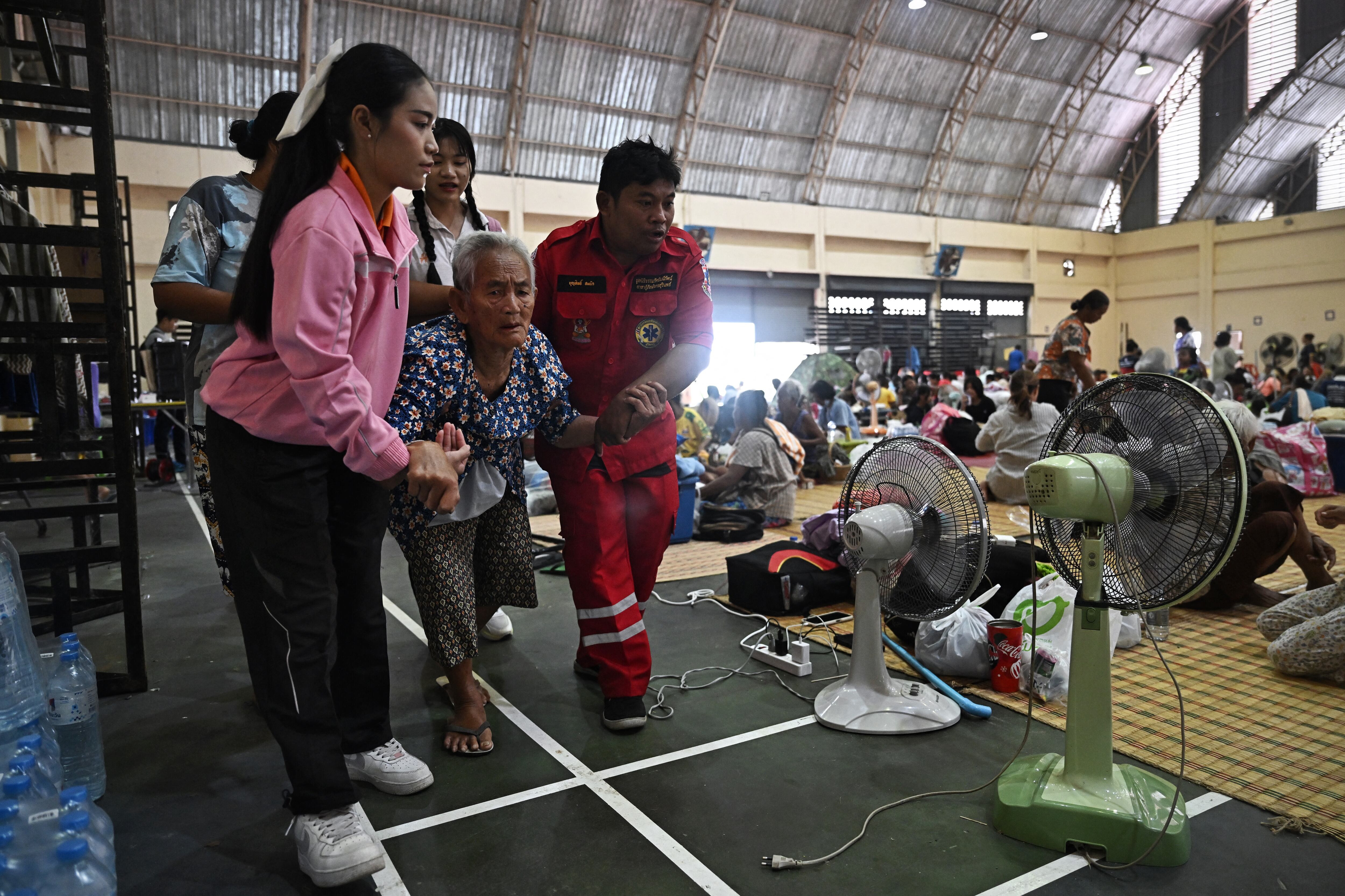Mujer adulta mayor asistida por rescatistas y voluntarios en un gimnasio habilitado como refugio en Tailandia, en medio de la evacuación de miles de personas por enfrentamientos en la frontera con Camboya