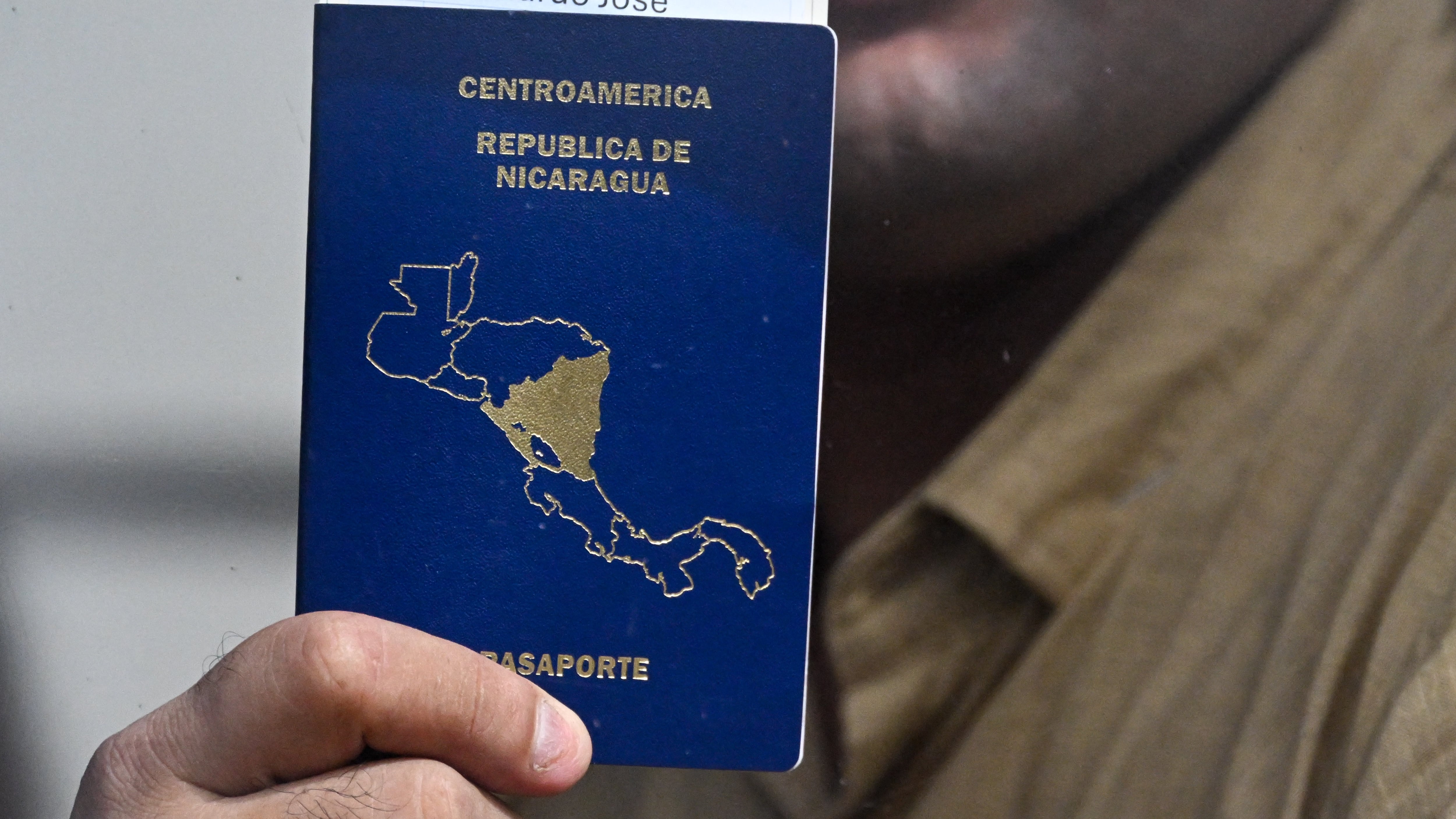 Uno de los 135 presos políticos muestra su pasaporte desde el autobús a lo interno del Aeropuerto La Aurora, en Ciudad de Guatemala. Foto: AFP