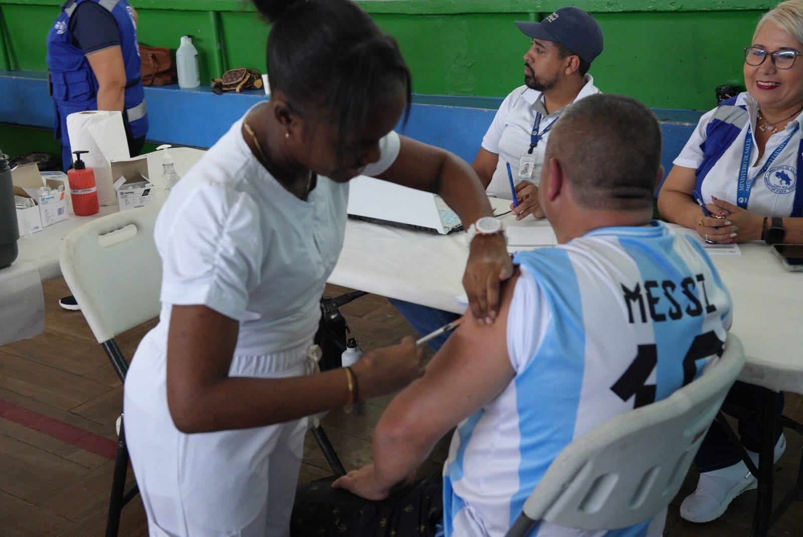 Enfermera vacuna a un hombre que viste la camiseta de Argentina con el nombre de Messi a la espalda.