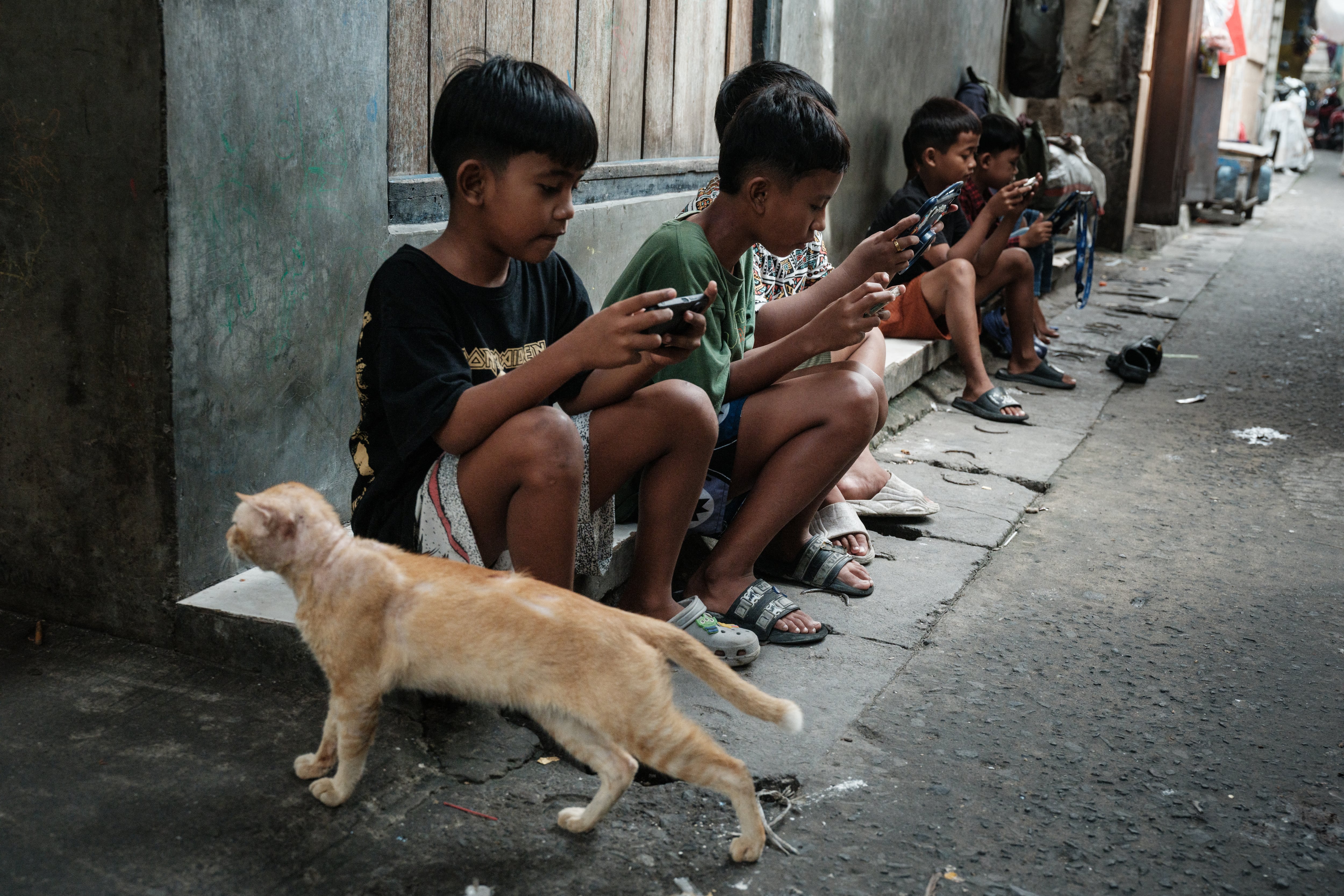 Niños juegan en línea entre sí en teléfonos inteligentes y tabletas en un callejón de Yakarta el pasado 26 de marzo. YouTube, TikTok, Facebook, Instagram, Threads, X, Bigo Live y Roblox, consideradas plataformas de "alto riesgo" por las autoridades de la nación del sudeste asiático, comenzarán a desactivar las cuentas de menores de edad desde este sábado.