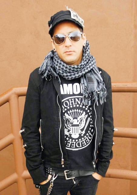 Imagen del expresentador de VM Latino Luis Lauretto vestido con gorra, lentes de sol, una bufanda, chaqueta negra y una camiseta de The Ramones.