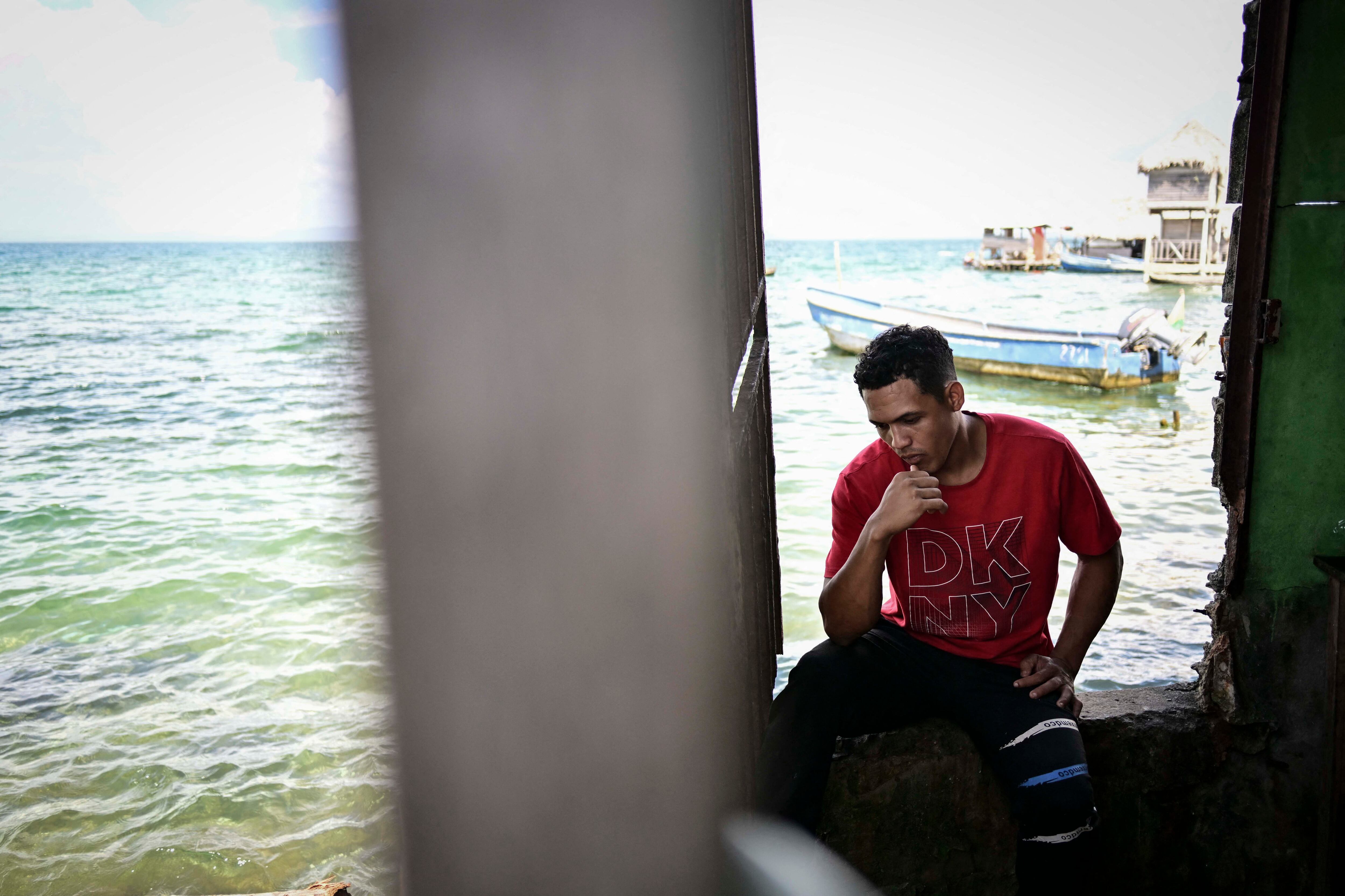 A Venezuelan migrant uses his phone as he waits to be transferred to Colombia by sea on the island of Carti, Guna Yala territory in Panama on February 24, 2025. Although Central American governments say they are trying to organize reverse migration, chaos r