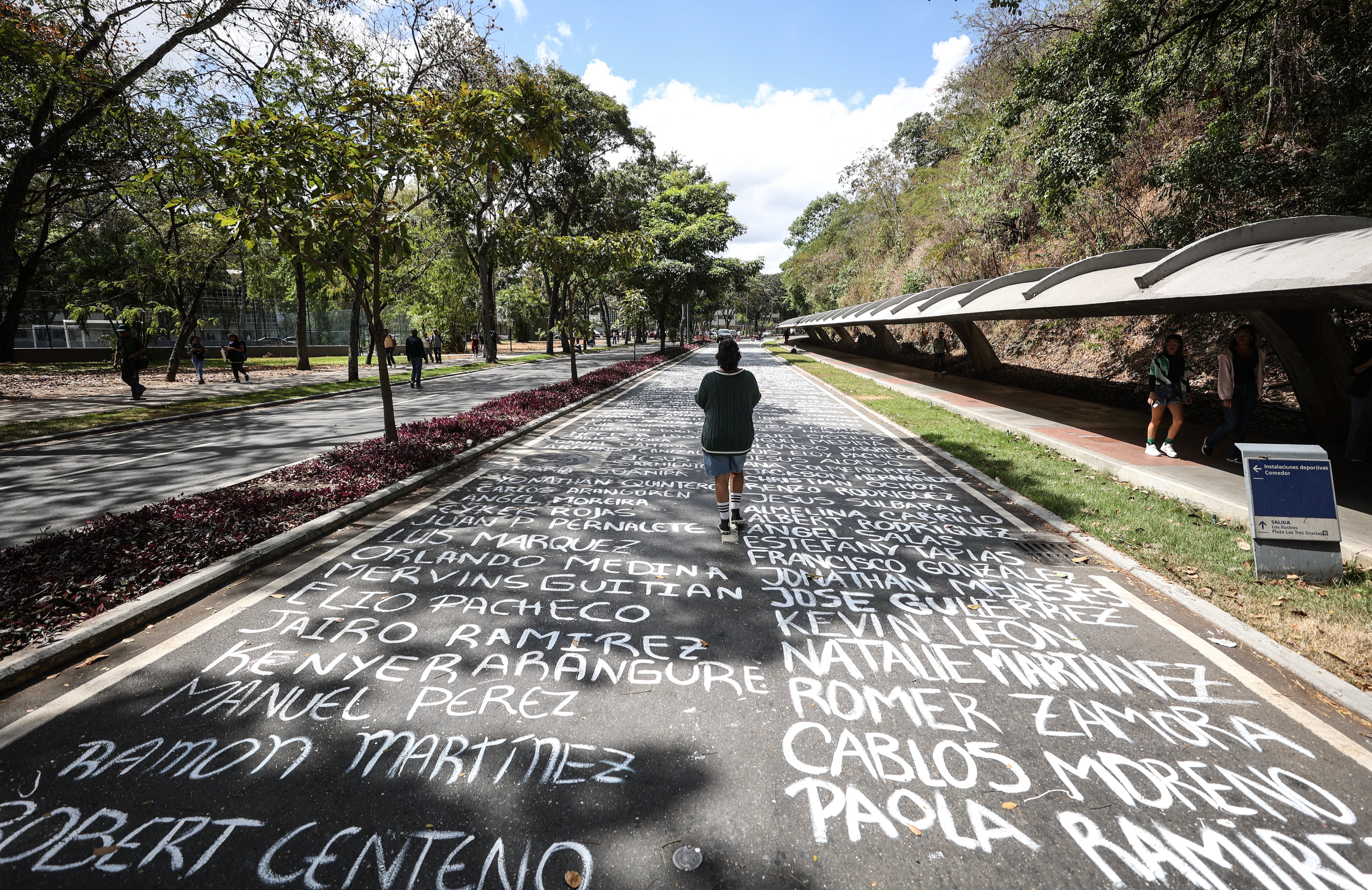 A student at the Central University of Venezuela walks over names of missing students painted on the floor of the university entrance in celebration of Venezuelan Youth Day in Caracas on February 12, 2025. (Photo by Pedro MATTEY / AFP)