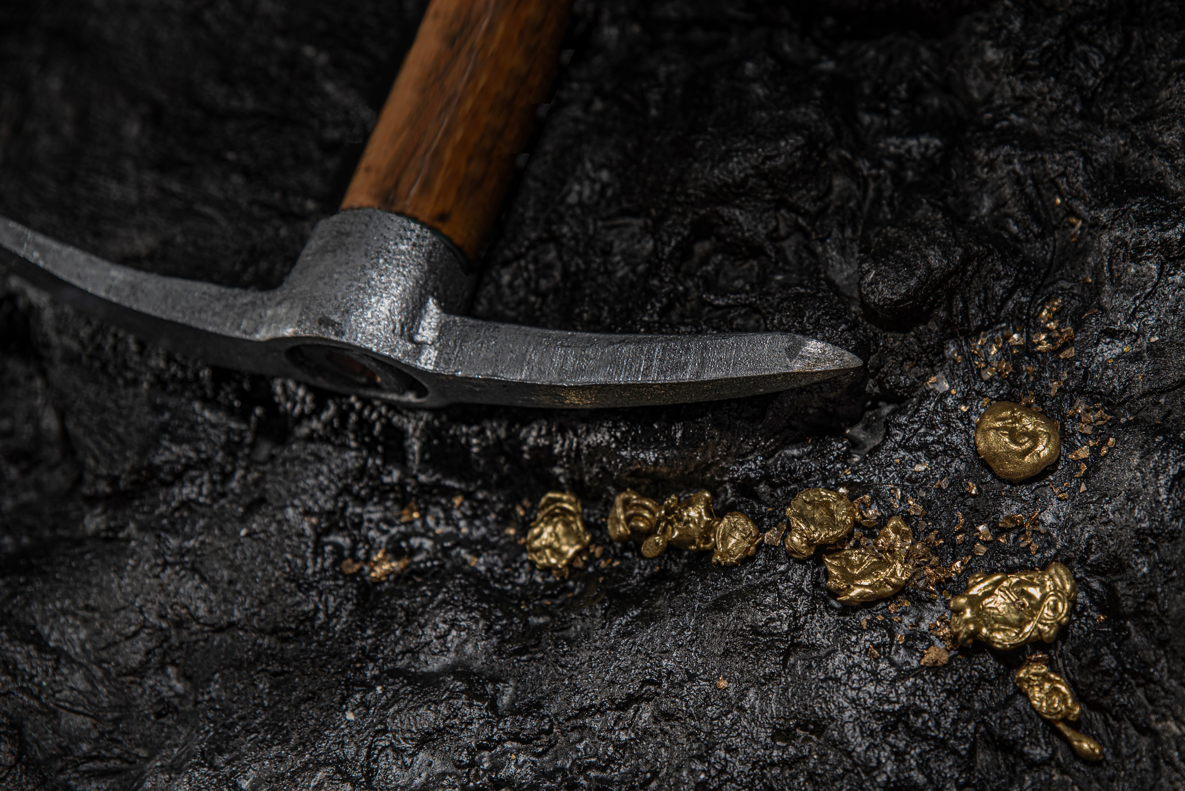 Mazo y pepitas de oro entre piedras sobre un fondo de roca en una mina subterránea, veta de oro. Explotación del oro. Coligalleros