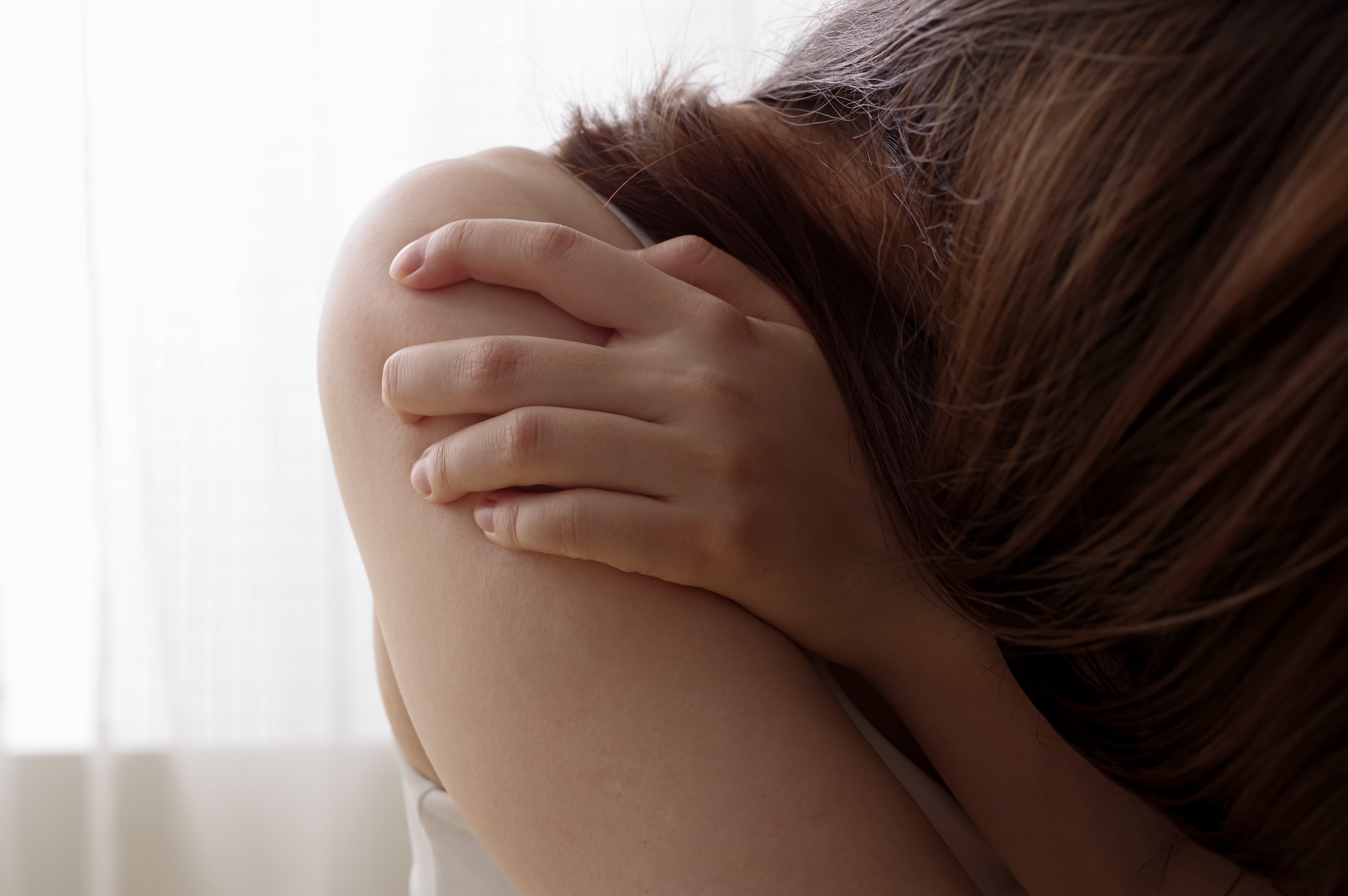 Mujer (con rostro no visible) intimidada, escondida, temerosa