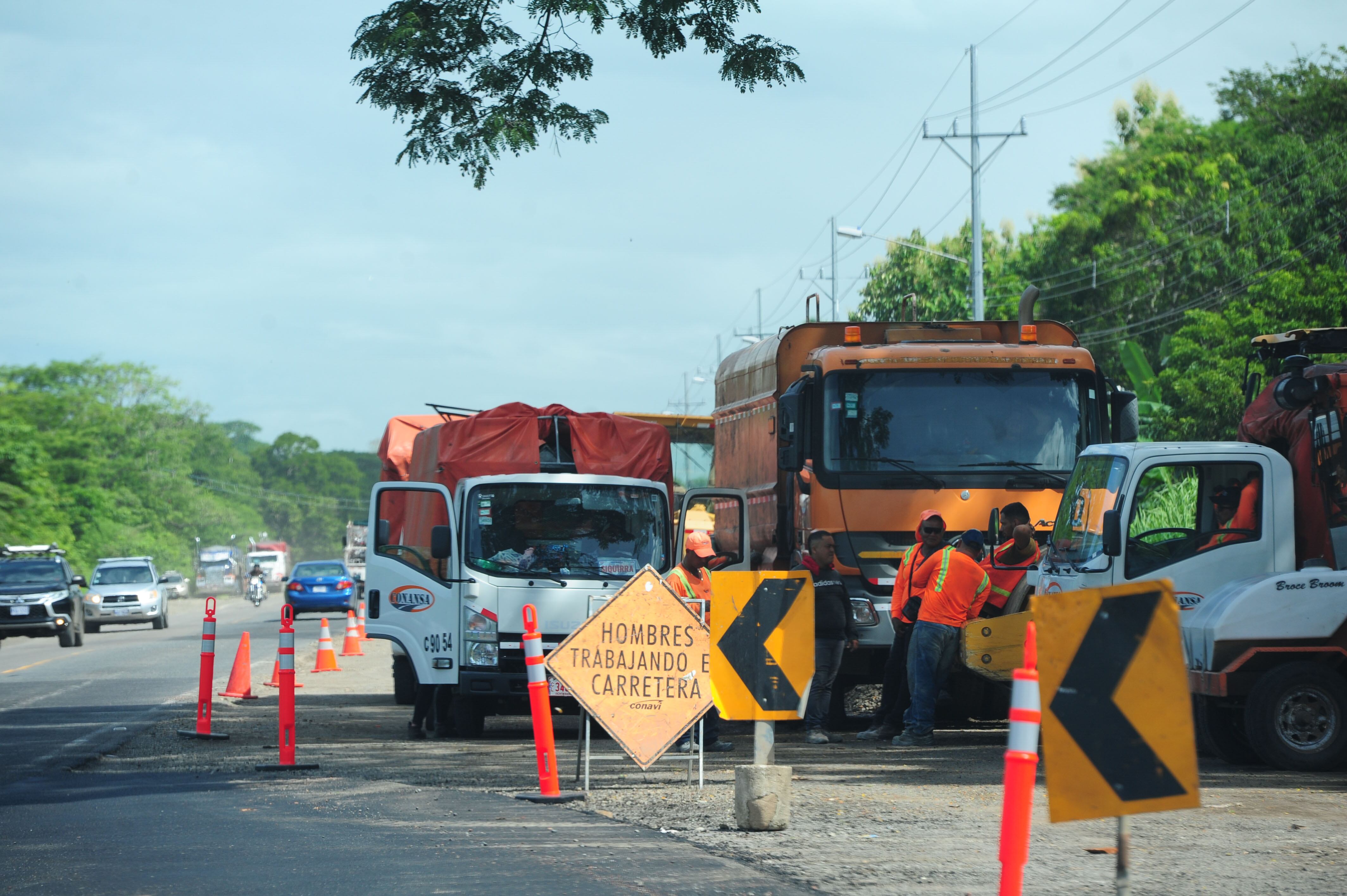 Vagonetas y maquinaria pesada a una orilla de la vía del tramo Barranca-Limonal, donde se colocó señalización de advertencia. Al lado se ven transitar los vehículos.