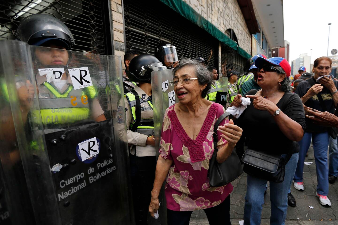 Adultas mayores pasaban el viernes frente a un destacamento de policías durante la 'marcha de los abuelos' en Caracas.
