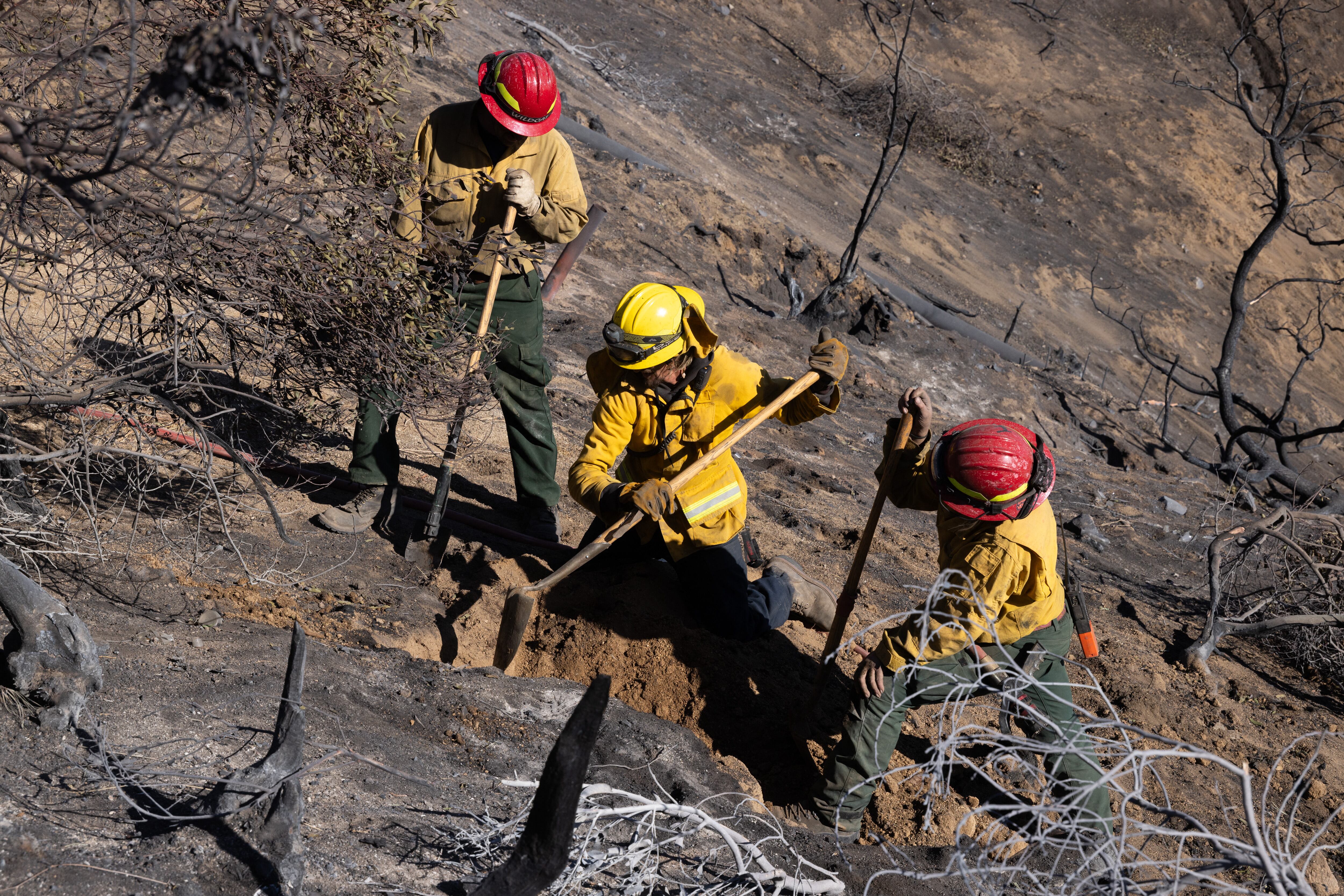 Los bomberos trabajan para apagar un foco de calor durante el incendio Eaton sobre Altadena, mientras los incendios forestales causan daños y pérdidas en toda la región de Los Ángeles.