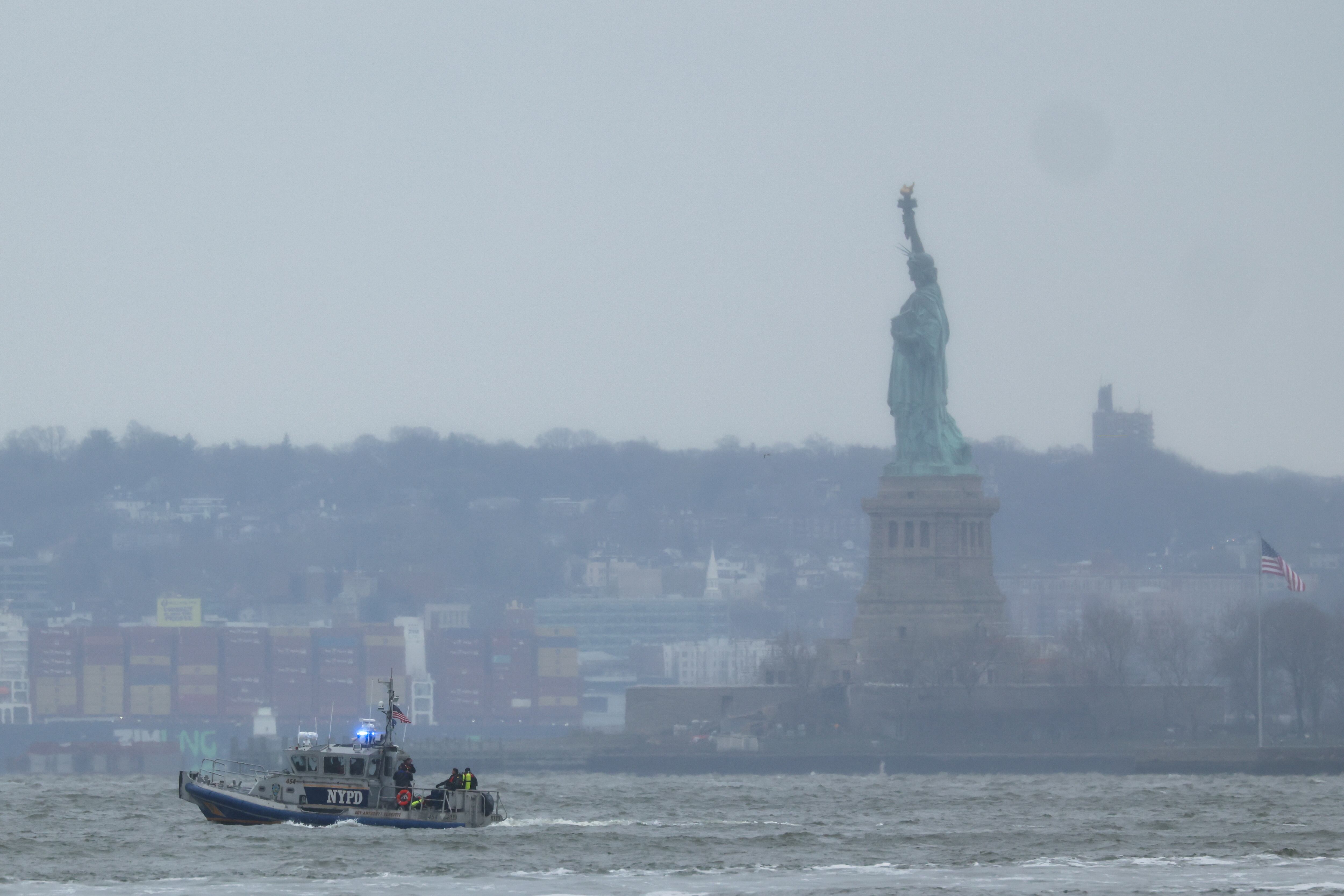 A New York Police Department rescue boat is seen near the Statue of Liberty in New York after a helicopter crashed into the Hudson River on April 10, 2025. A helicopter crashed into the Hudson River in New York, emergency services said, as local media reported multiple deaths in the incident. Several people were pulled from the water and taken to a hospital in New Jersey, the NBC4 broadcaster reported citing law enforcement at the scene, adding that four had died. (Photo by CHARLY TRIBALLEAU / AFP)