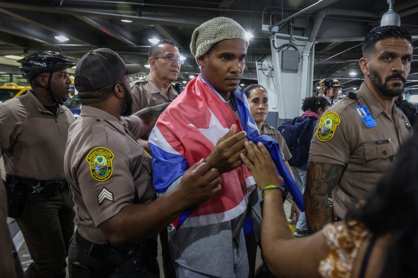 Luis Manuel Otero Alc�ntara, artist and opponent of the Cuban regime, is escorted by members of the Miami Police Department upon his arrival at Miami International Airport on July 18, 2026. Prominent Cuban dissident artist Luis Manuel Otero Alcantara flew to exile Saturday in the United States after serving a five-year sentence on the island, as Washington urged Havana to release more than 700 political prisoners. (Photo by Giorgio Viera / AFP)