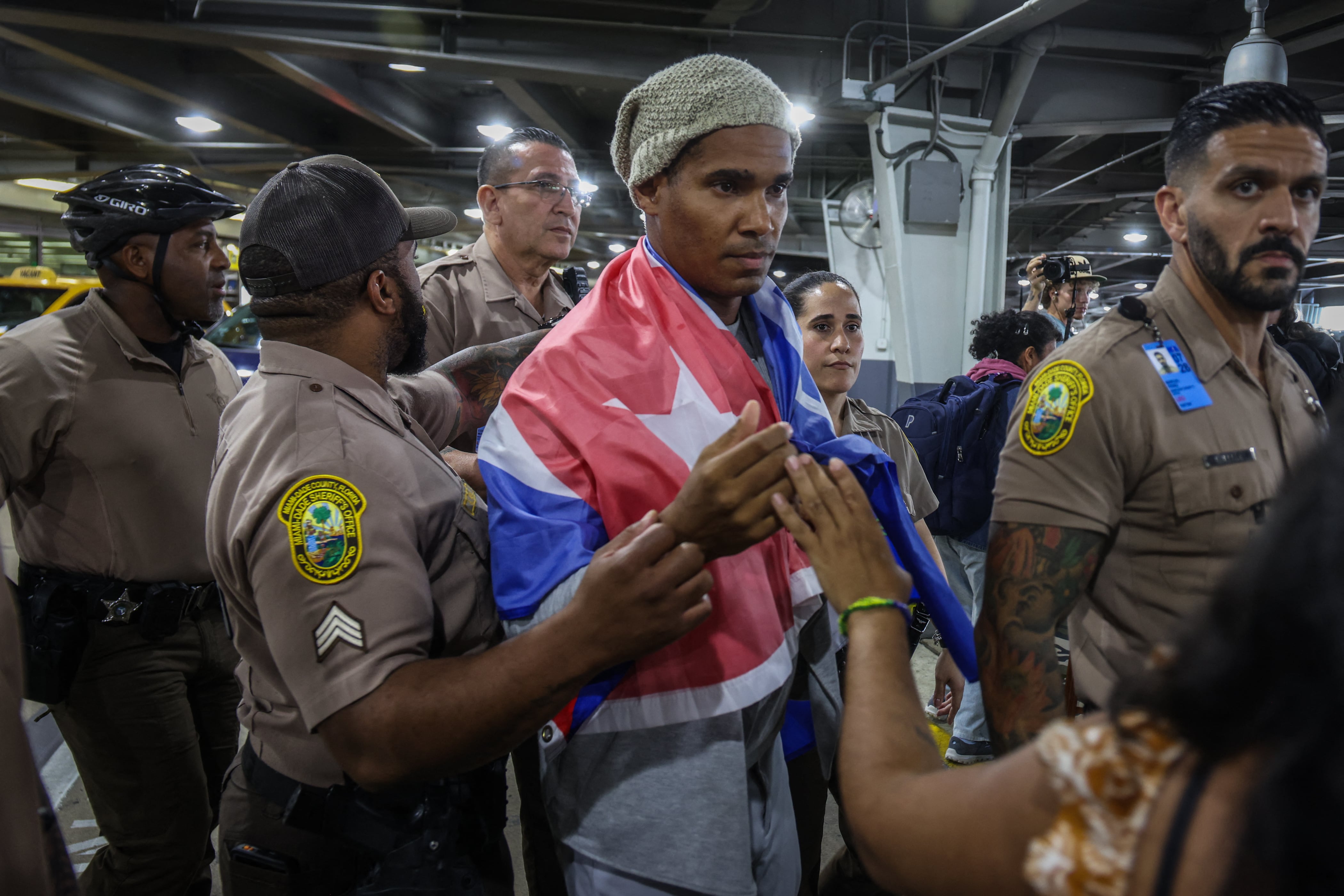 Luis Manuel Otero Alc�ntara, artist and opponent of the Cuban regime, is escorted by members of the Miami Police Department upon his arrival at Miami International Airport on July 18, 2026. Prominent Cuban dissident artist Luis Manuel Otero Alcantara flew to exile Saturday in the United States after serving a five-year sentence on the island, as Washington urged Havana to release more than 700 political prisoners. (Photo by Giorgio Viera / AFP)