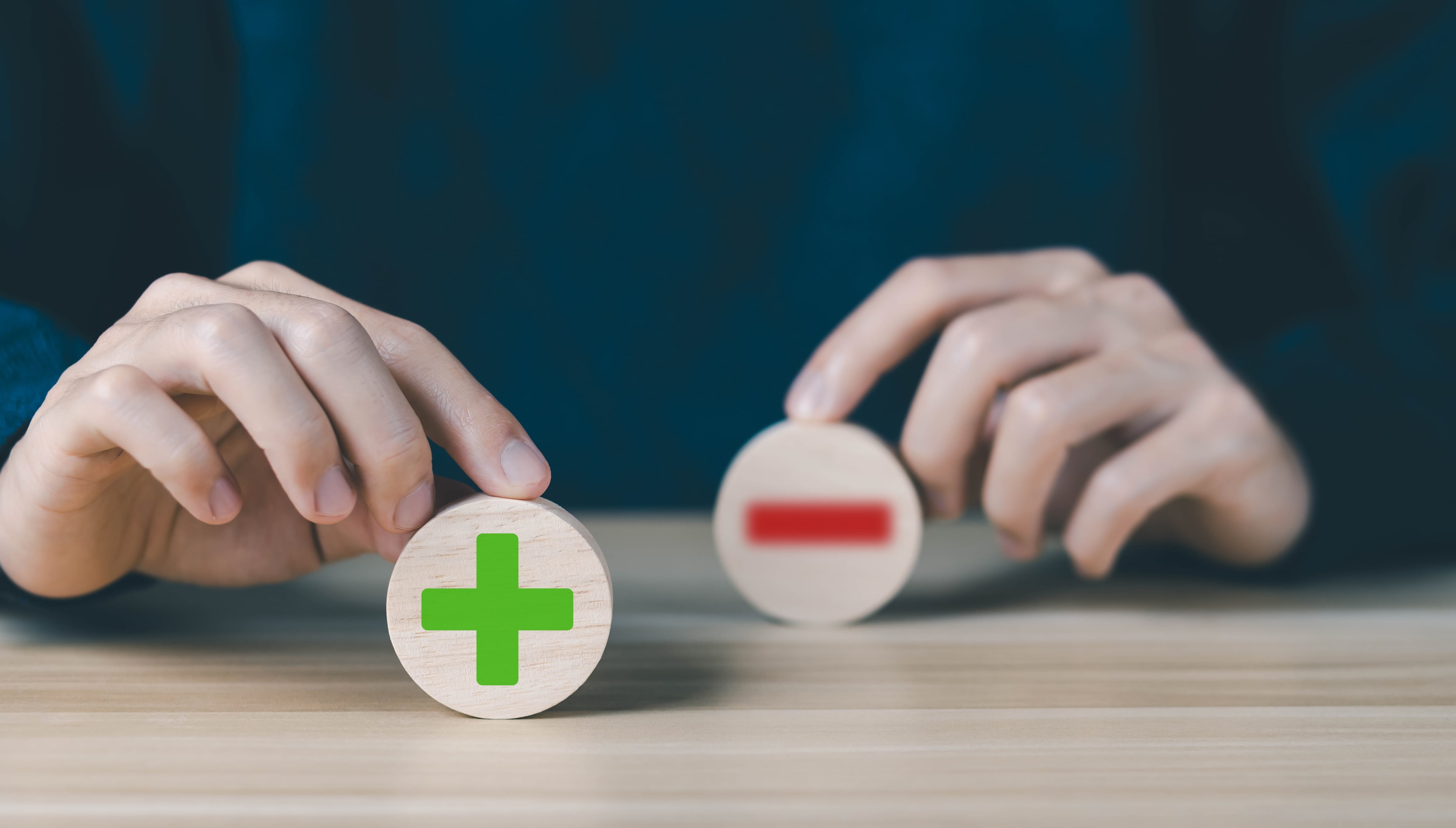 Signos de más y menos, suma y resta, sumar y restar. Manos sostienen piezas con los símbolos