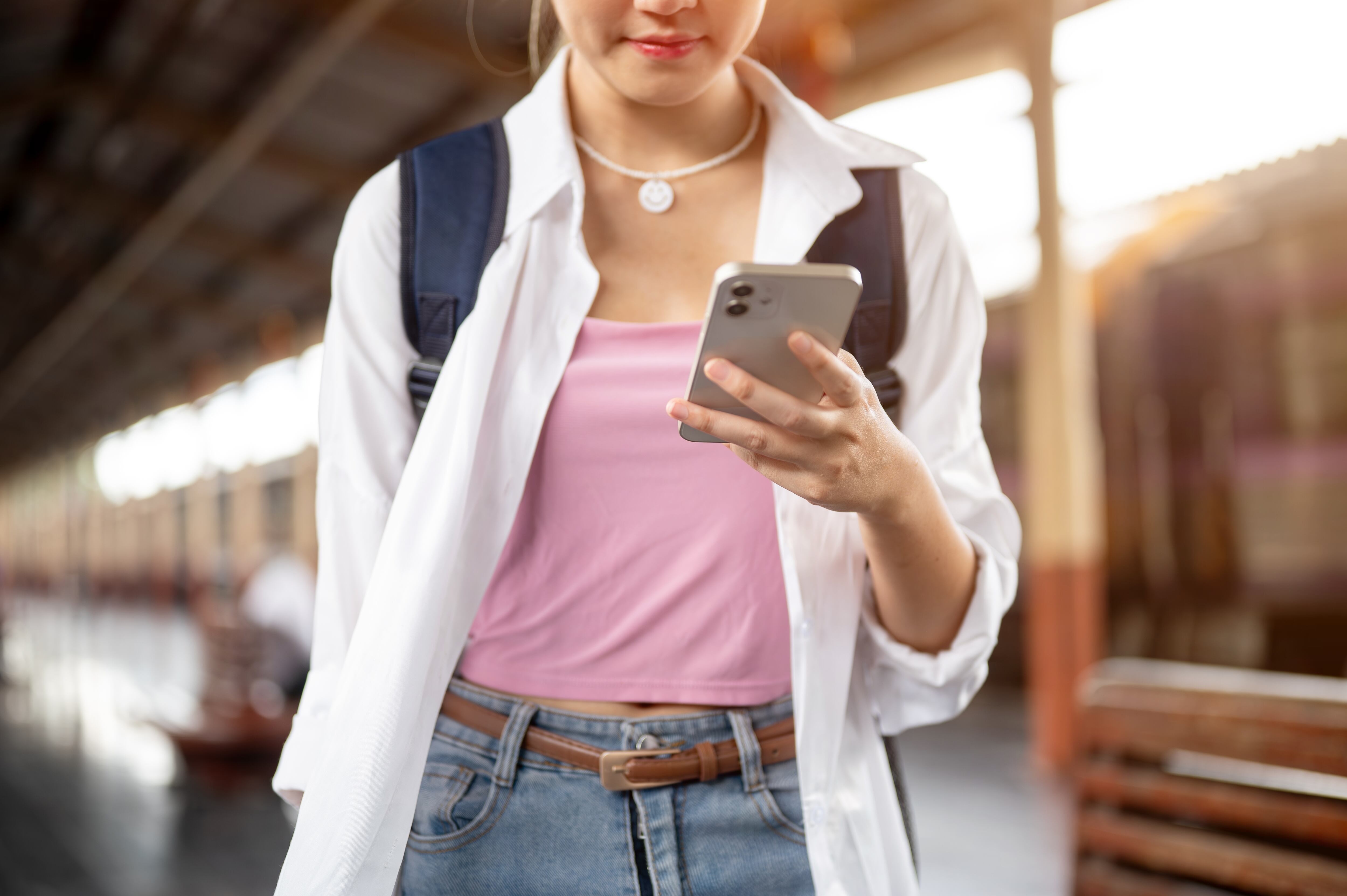 Mujer joven camina mientras ve la pantalla de su celular
