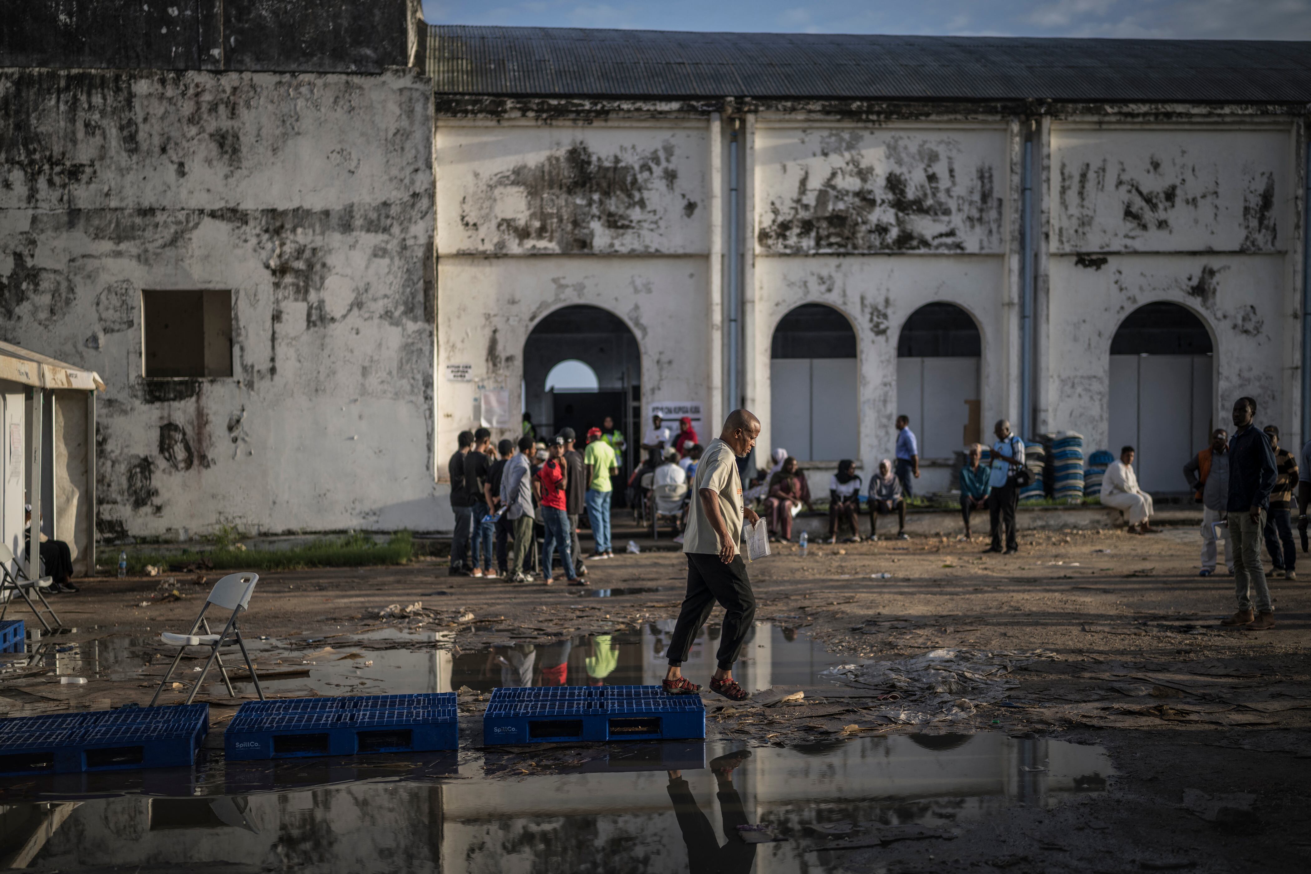 Un hombre baja de unas plataformas colocadas sobre un charco en el centro de votación Maundi en Stone Town el 29 de octubre de 2025, durante las elecciones presidenciales de Tanzania.