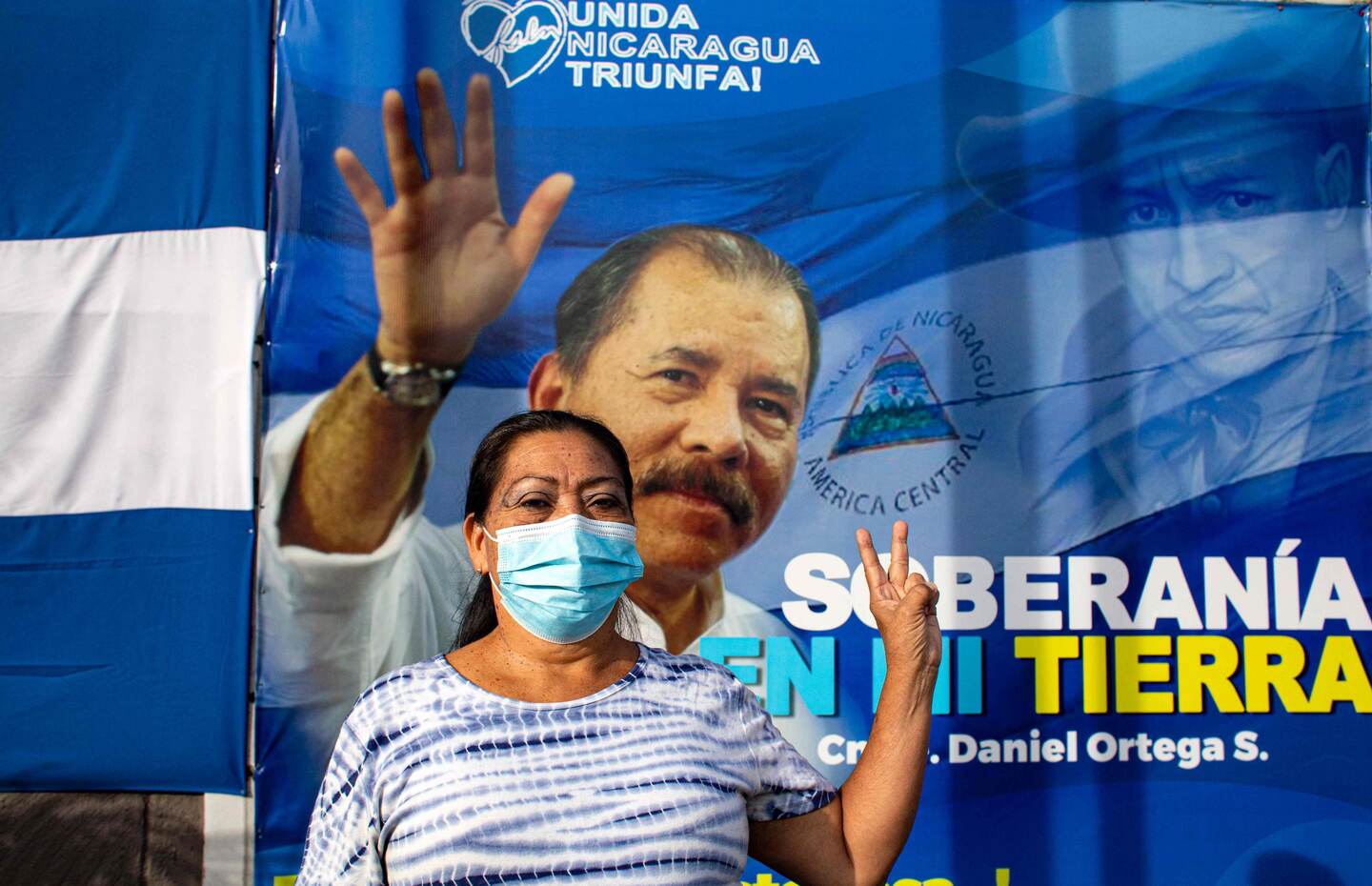 A woman gestures in front of a banner promoting Nicaragua's President Daniel Ortega candidacy in Managua on September 24, 2021. - Nicaragua officially kicks off campaigning for the 7 November presidential elections on Saturday, with President Daniel Ortega's main rivals arrested and the way clear for him to seek a fourth consecutive term in office. (Photo by OSWALDO RIVAS / AFP)