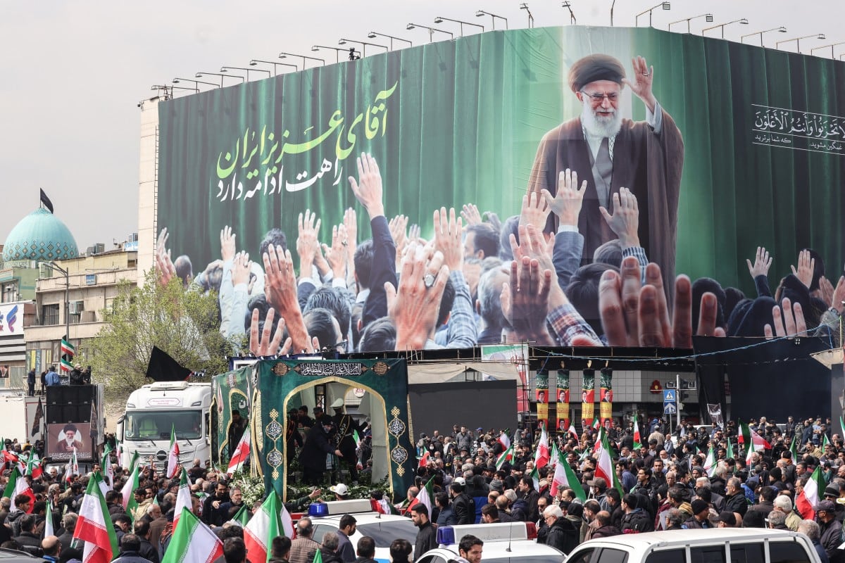 Iraníes se reúnen junto a un cartel que representa al líder supremo iraní abatido, el ayatolá Ali Khamenei, mientras asisten a los funerales de comandantes de la Guardia Revolucionaria de Irán (IRGC).