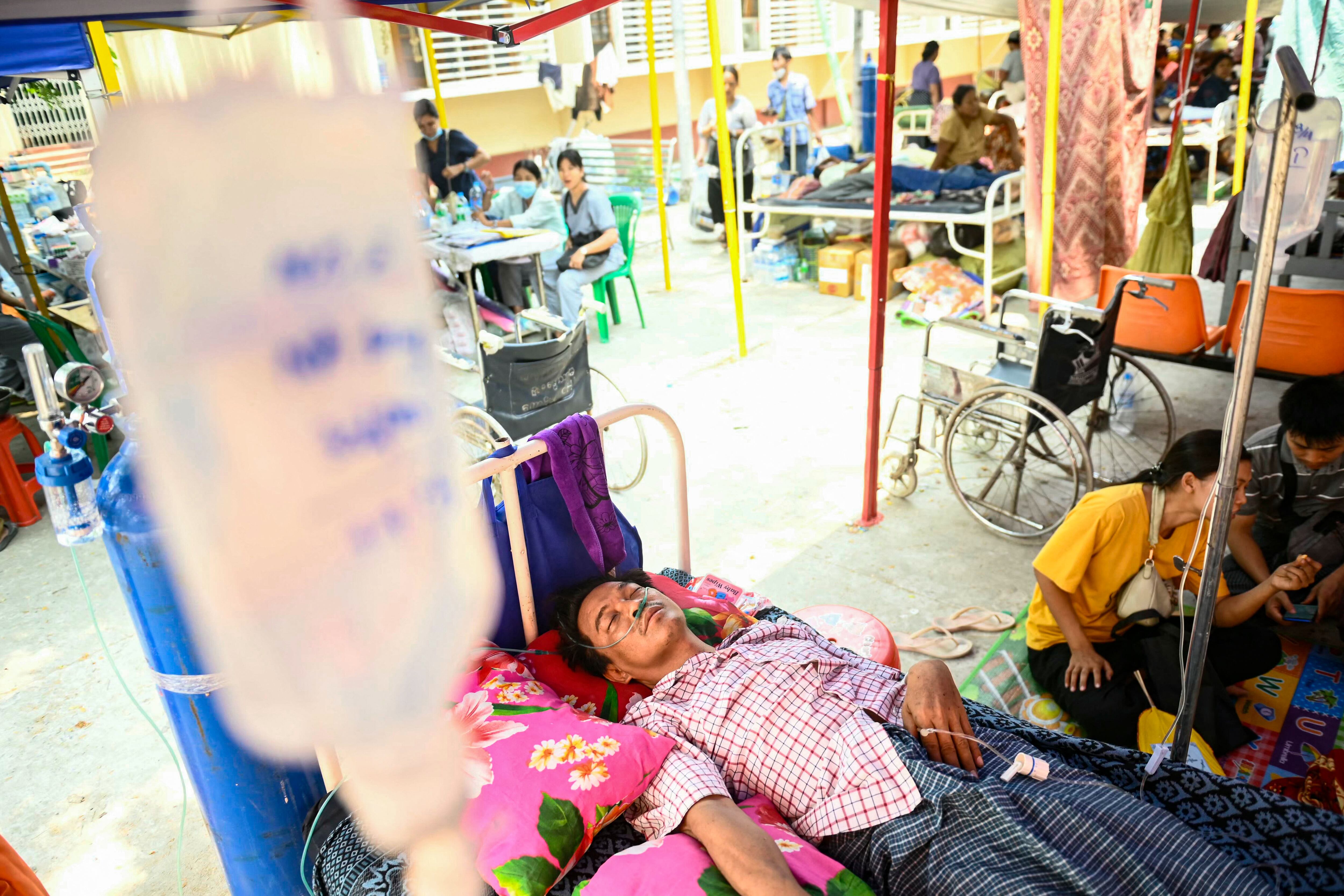 El sobreviviente Tin Maung Htwe yace en una cama dentro del recinto de un hospital mientras recibe tratamiento, un día después de ser rescatado de las ruinas de un hotel en Sagaing, el 3 de abril de 2025, tras el terremoto del 28 de marzo.
Atrapado bajo la cama de su hotel durante cinco días entre los escombros, dos cosas le permitieron al maestro Tin Maung Htwe sobrevivir al devastador terremoto en Birmania: sus antiguas lecciones escolares y su propia orina.