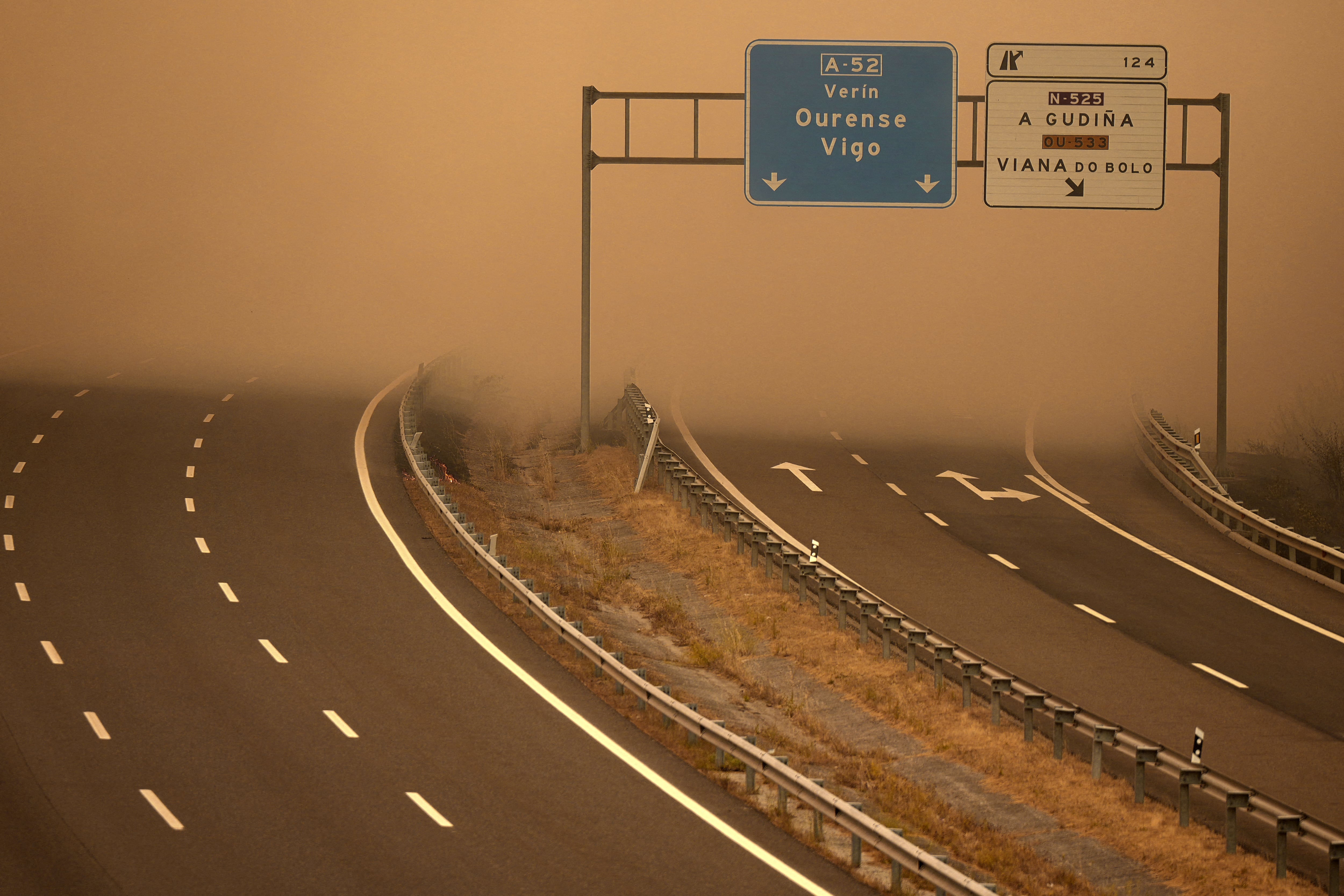 Thick smoke from a wildfire covers a highway in A Gudina, northwestern Spain, on August 15, 2025. All of Spain was on a heatwave alert today, while the weather agency warned that much of the country was at "very high to extreme risk" from wildfires. Nearly two weeks of high temperatures have left Spain sweltering, and today spread to Cantabria, which has so far been spared from the searing heat. Temperatures in the northwestern region were forecast to pass 40C, the national meteorological agency, Aemet, said. Spain has endured a devastating season of fires, with 157,501 hectares (389,193 acres) reduced to ashes since the start of the year, according to data from the European Forest Fire Information System (EFFIS). (Photo by Cesar Manso / AFP)
