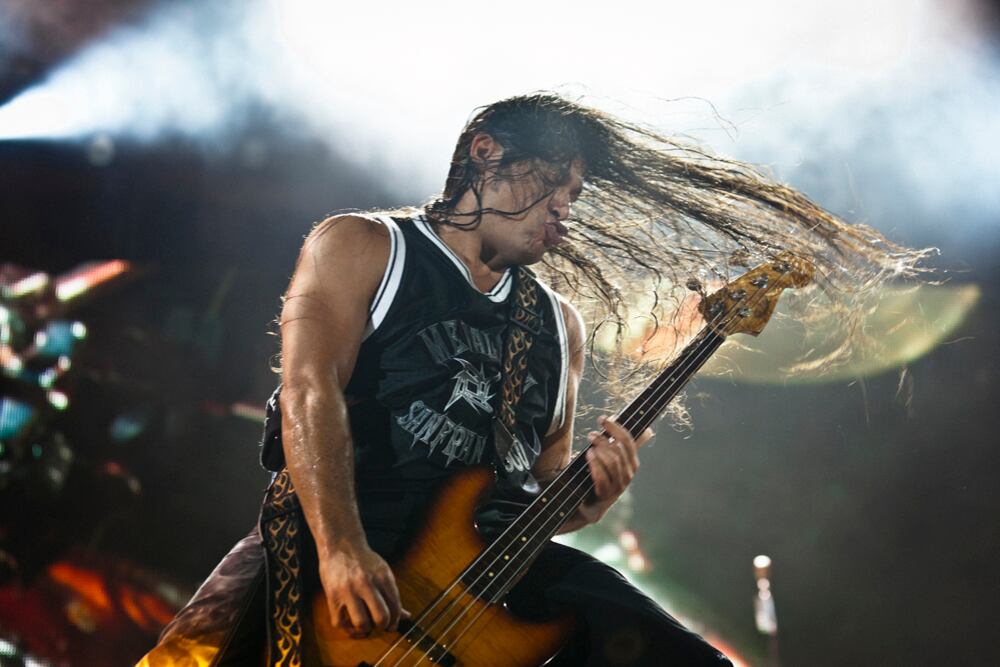 Foto de Robert Trujillo tocando su bajo en concierto.