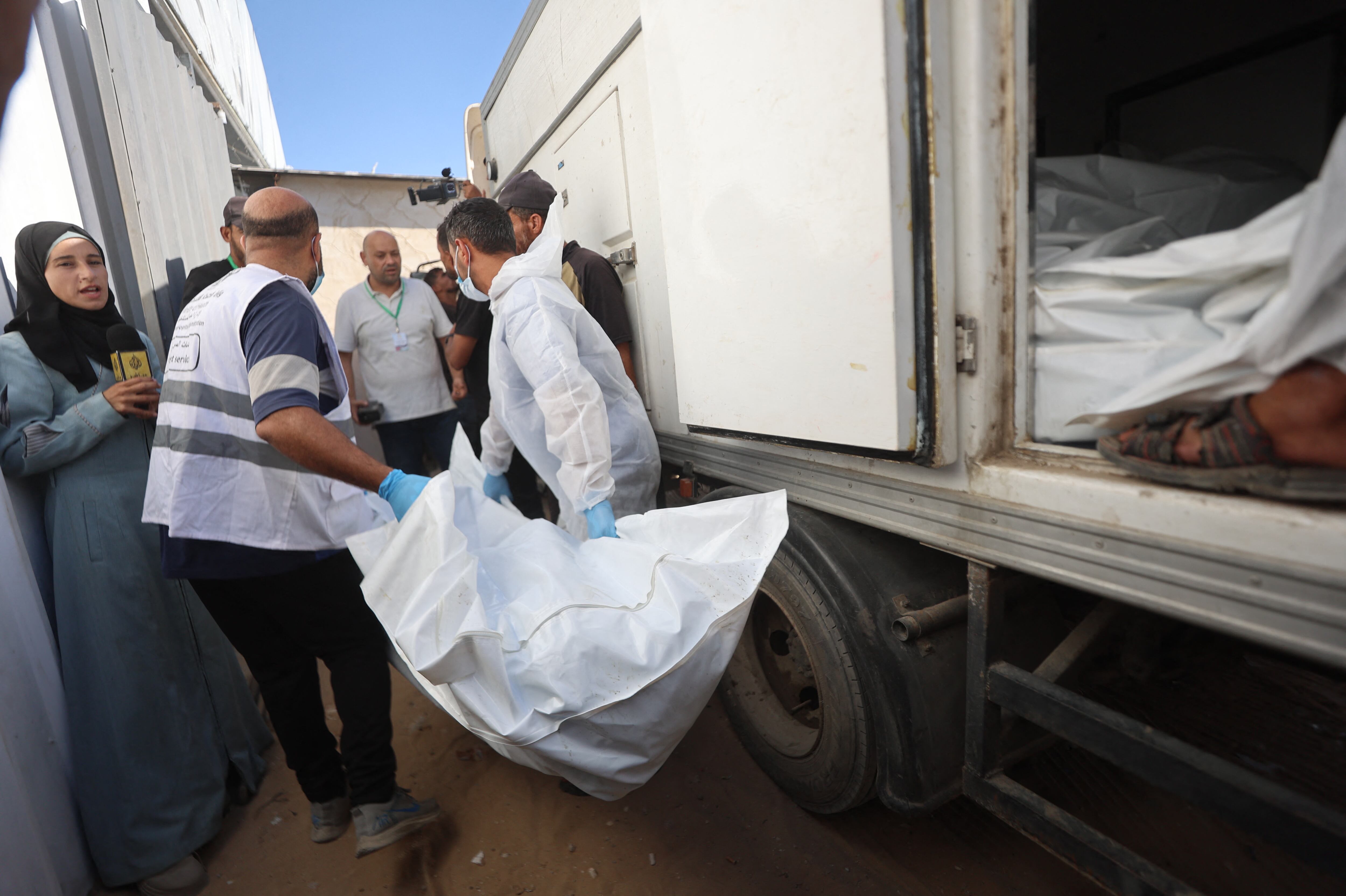 Trabajadores de la morgue descargan los cuerpos de palestinos que habían estado bajo custodia israelí, tras ser transportados en vehículos de la Media Luna Roja y camiones refrigerados, al hospital Nasser de Khan Yunis, en el sur de la Franja de Gaza, el 15 de octubre de 2025.
