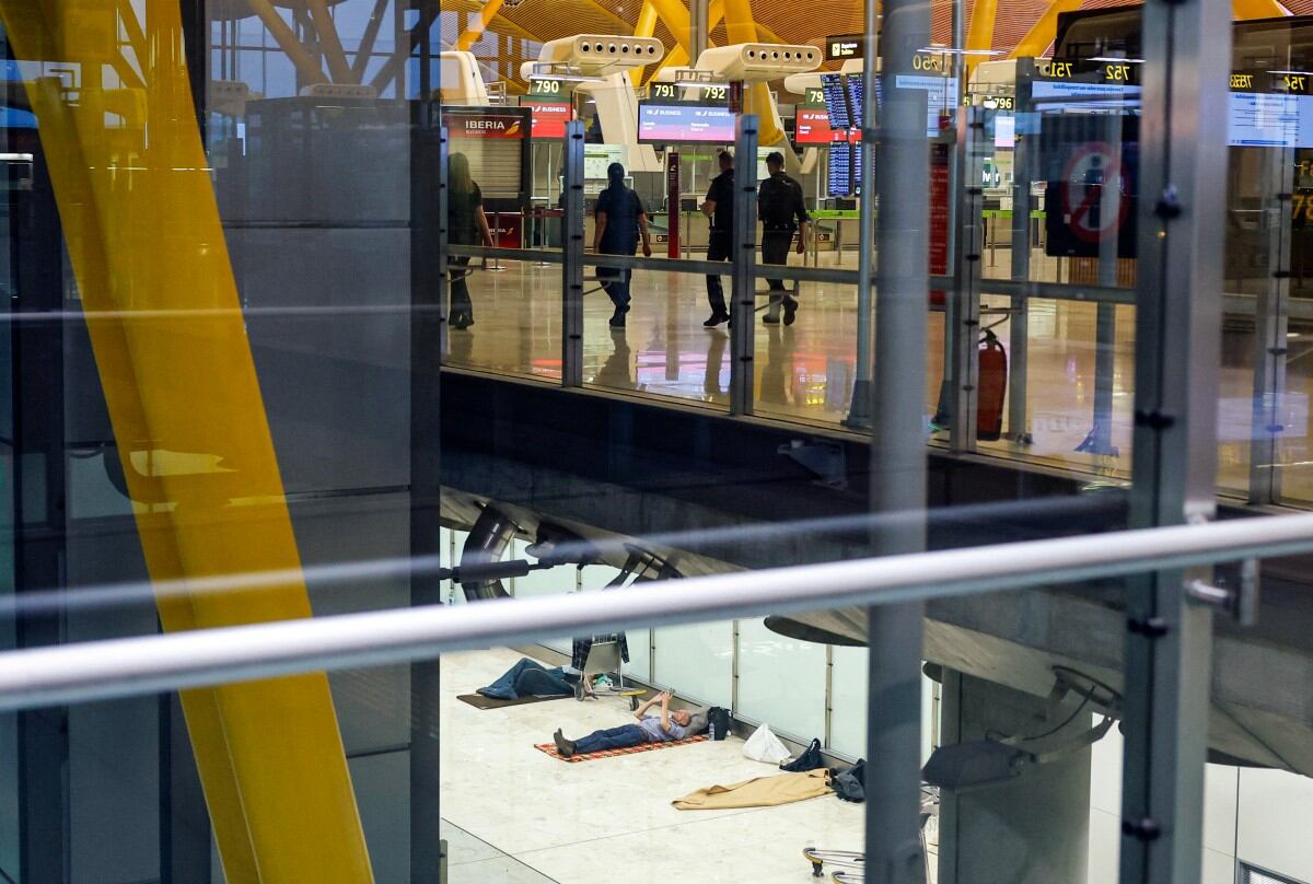 Pasajeros (arriba) se dirigen a sus vuelos mientras personas sin hogar (abajo) yacían en el suelo de la Terminal 4 del aeropuerto Adolfo Suárez Madrid-Barajas, Madrid, el 28 de mayo de 2025.