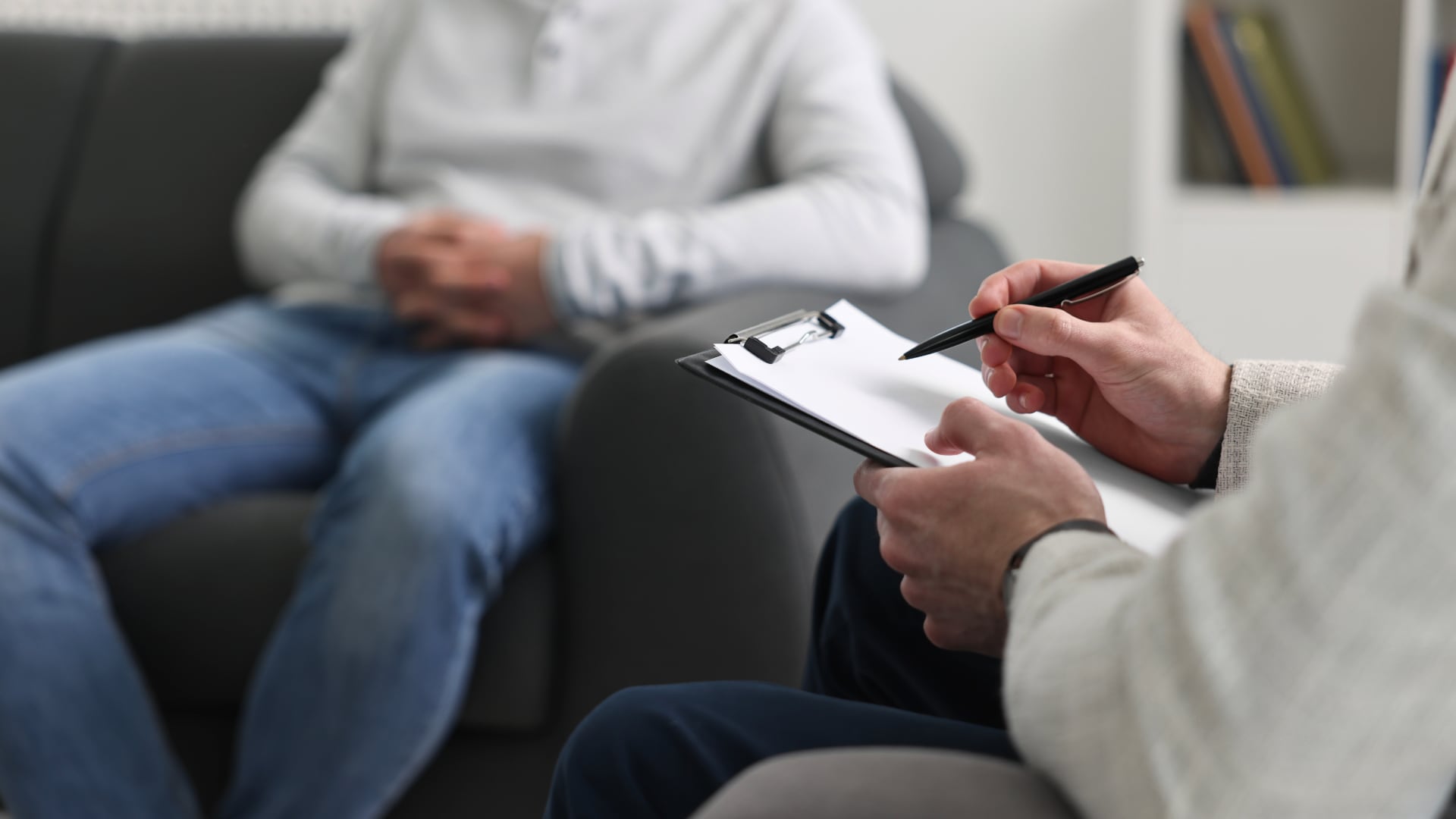 Persona, paciente, en consulta de salud mental, con el psicólogo, psicoterapeuta, psiquiatra, quien está tomando notas