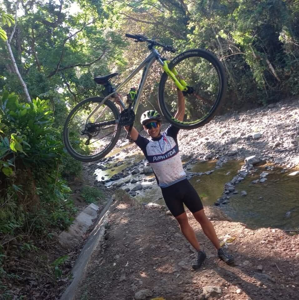 Un joven sosteniendo una bicicleta en señal de victoria.