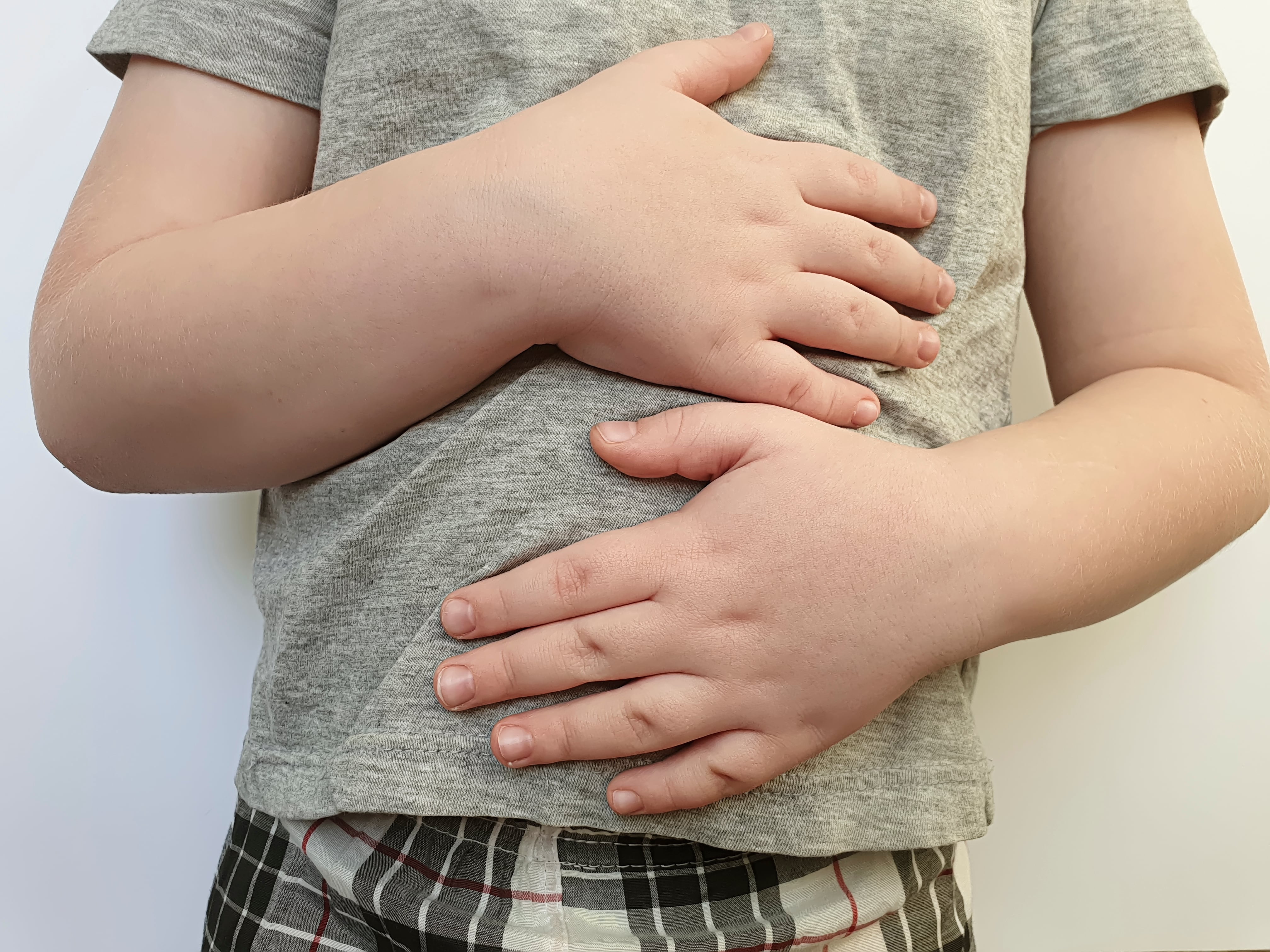 Plano cerrado de niño con dolor de estómago, con las manos colocadas sobre el abdomen