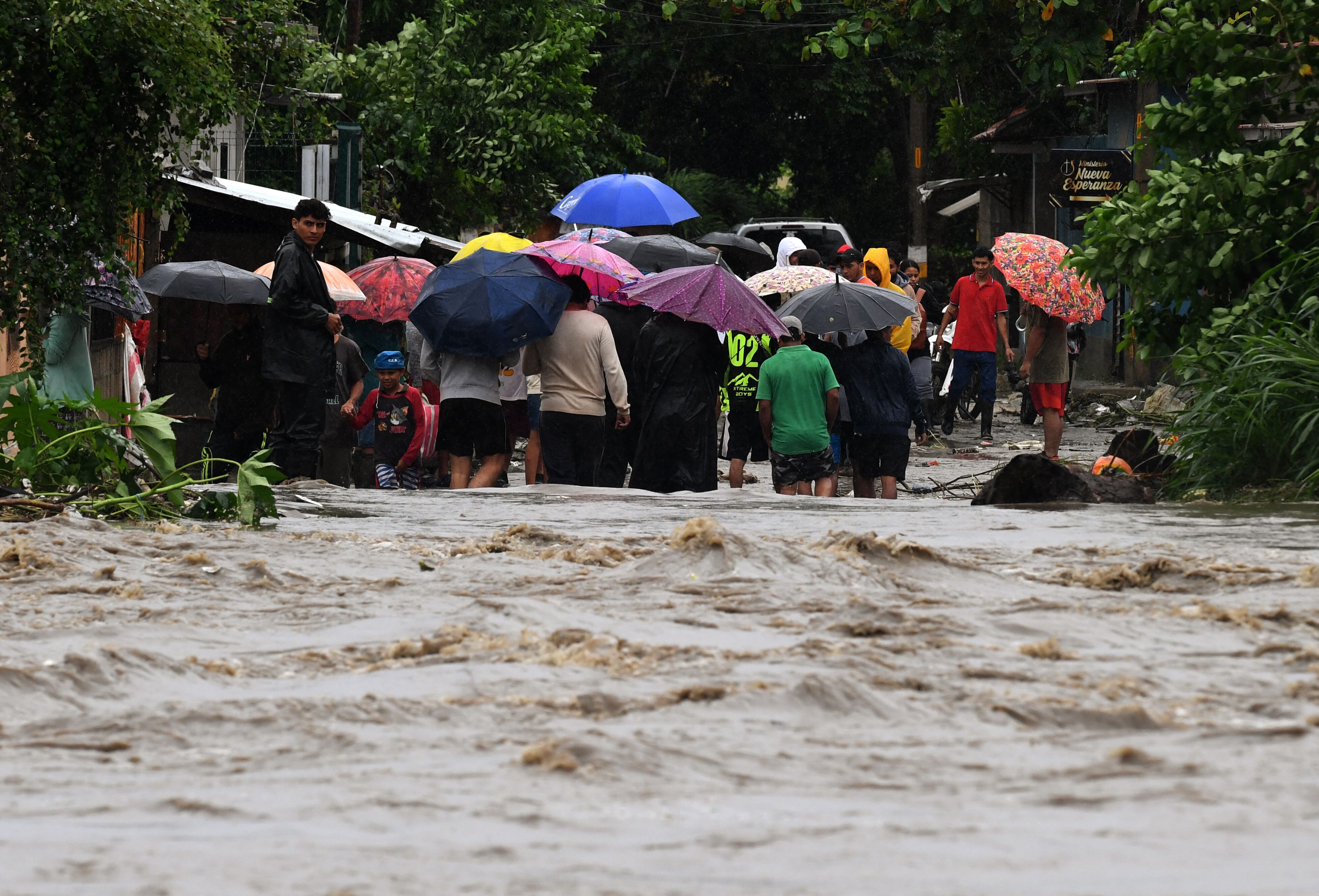 Personas se alejan del río Bermejo inundado en San Pedro Sula, Honduras, debido a las fuertes lluvias que dejó la tormenta tropical Sara.