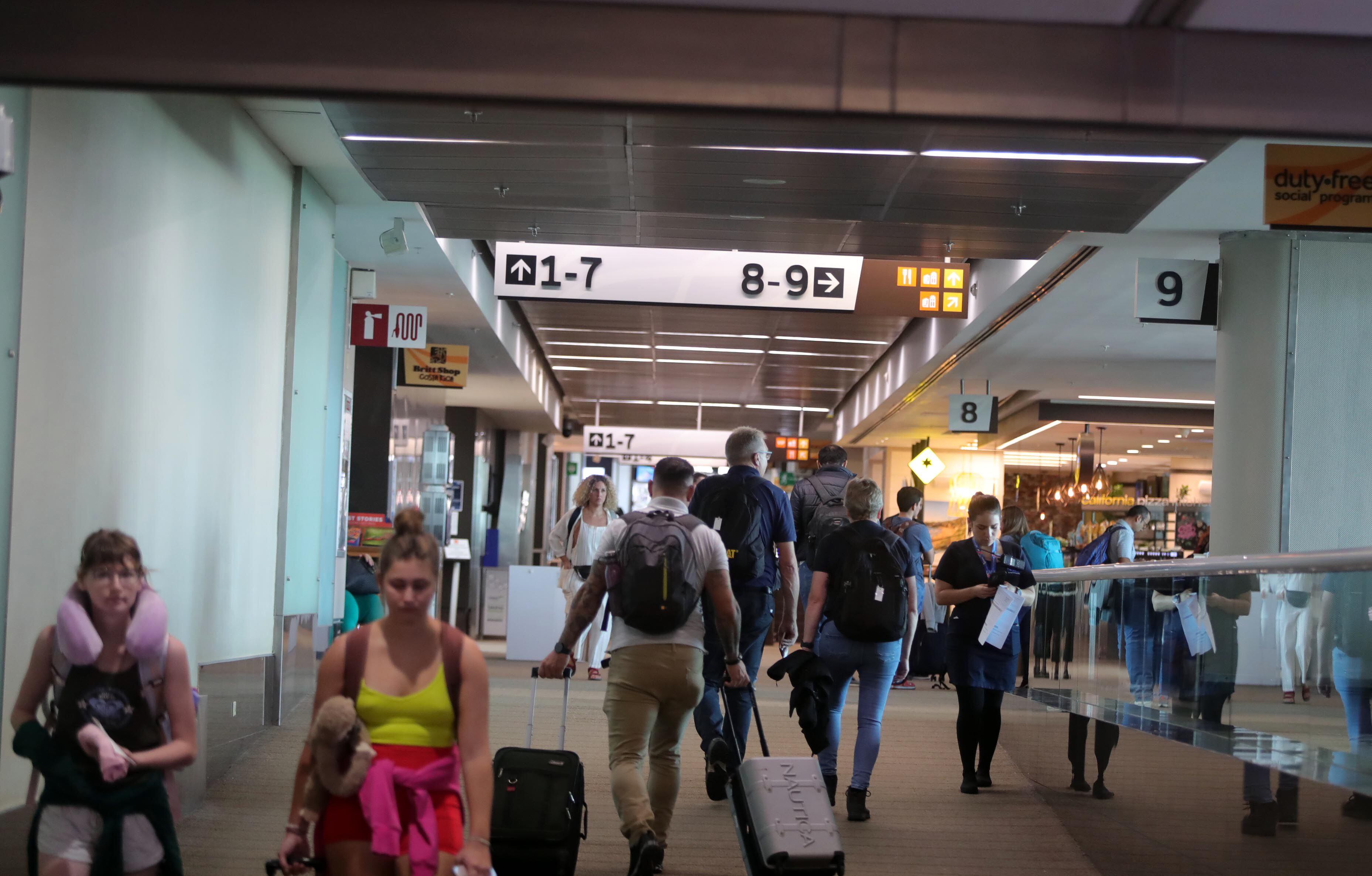 Grupo de pasajeros esperando en un aeropuerto tras la cancelación de su vuelo, con maletas y expresiones de preocupación. El Convenio de Montreal protege sus derechos ante retrasos y cancelaciones.