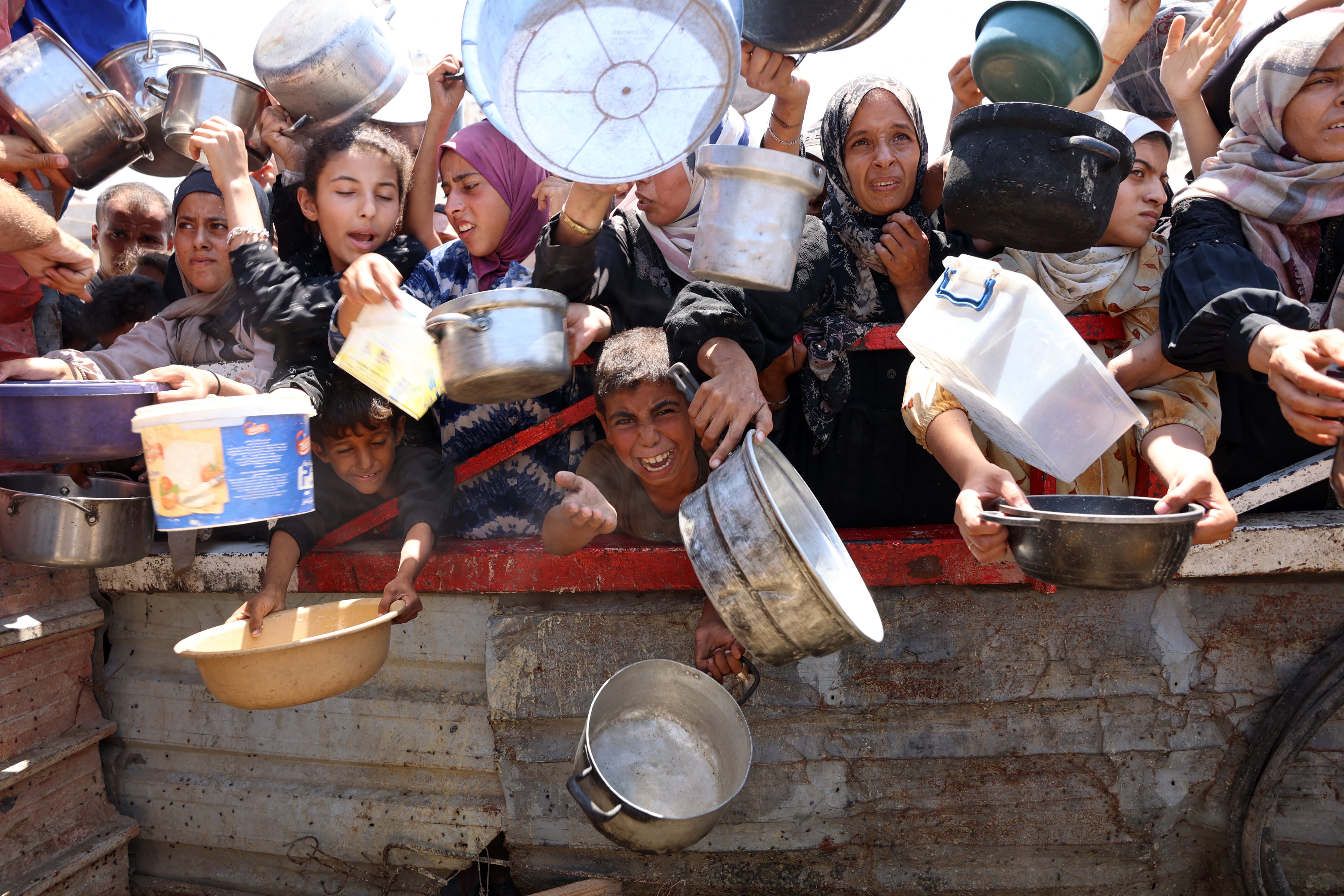 Palestinos se congregan en un punto de distribución de sopa de lentejas en la ciudad de Gaza, al norte de la Franja de Gaza, el 27 de julio de 2025. (Foto de Omar AL-QATTAA / AFP)