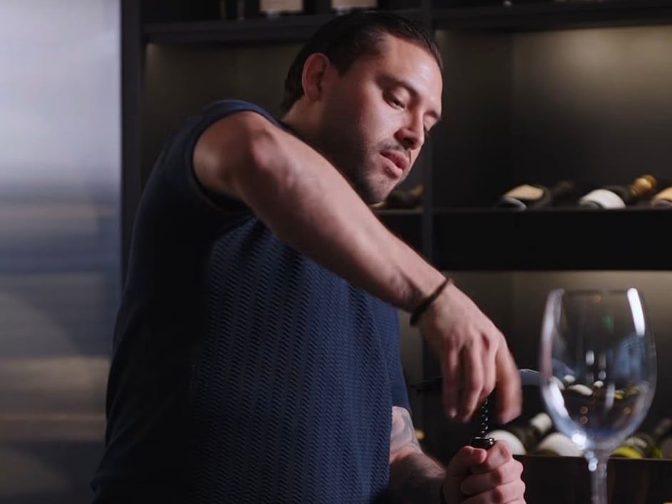 David Ramírez abre una botella de vino en su restaurante De La Vid.