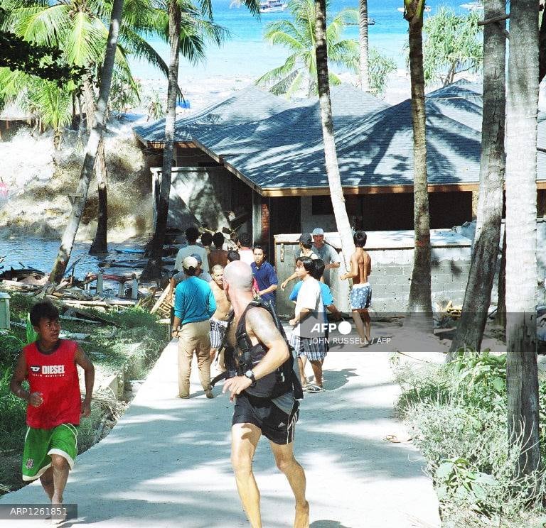 Esta foto, tomada el 26 de diciembre de 2004, muestra a gente huyendo mientras una ola de tsunami llega a la costa de Koh Raya, parte del territorio tailandés en las islas Andamán. (Foto de John RUSSELL / AFP)
