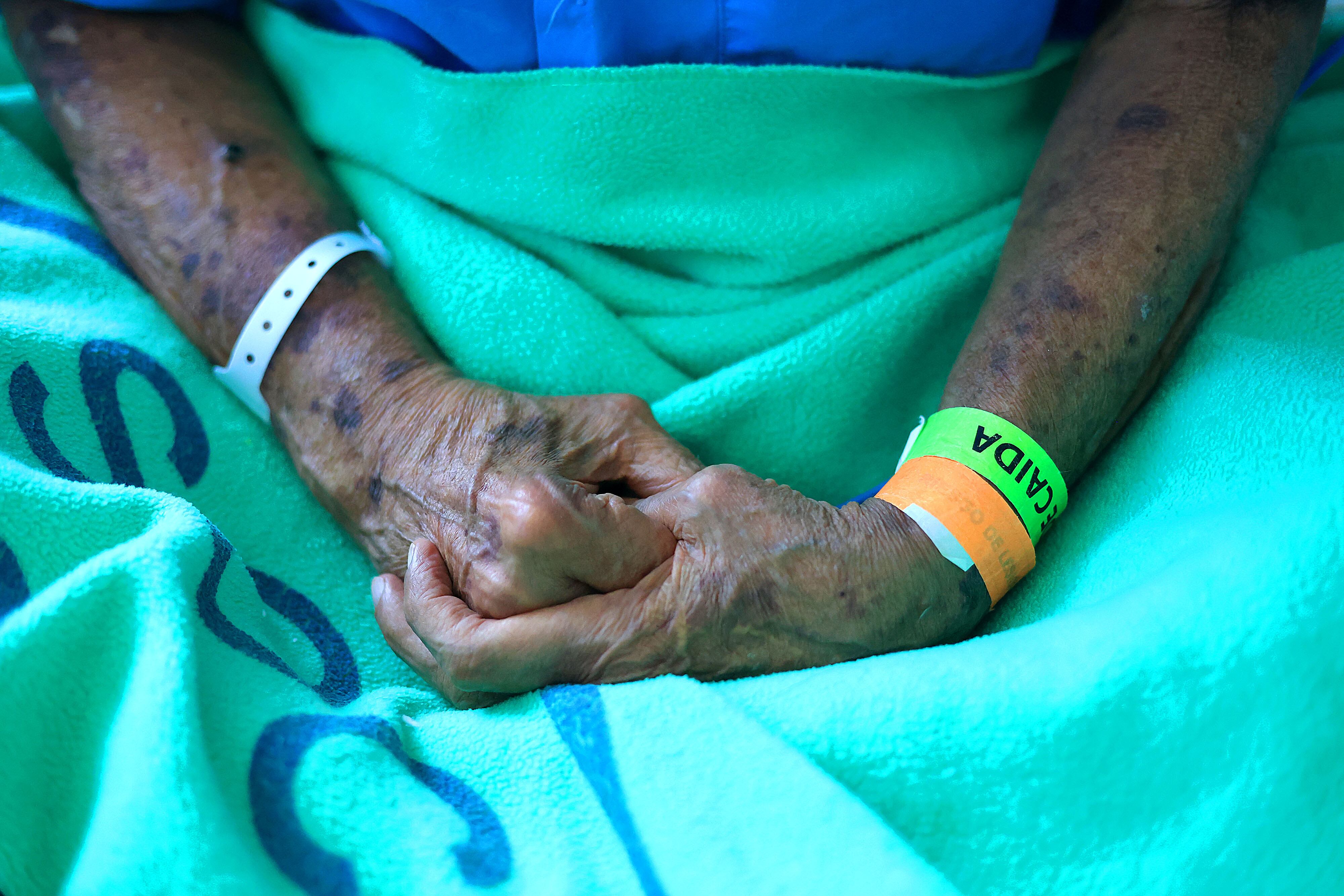 detalle de manos de adulto mayor entrelazadas.