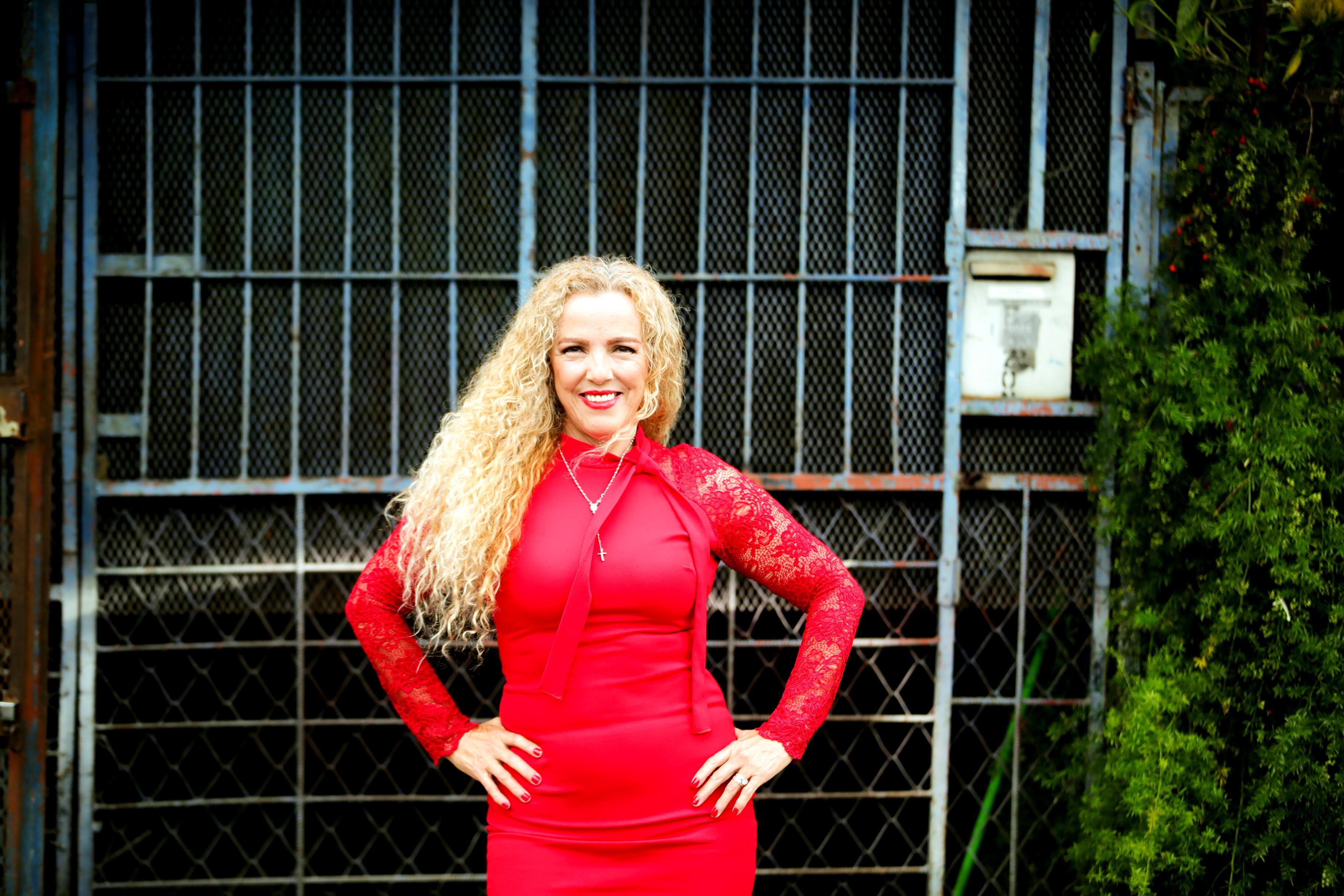 La costarricense Ana Rita Rojas en primer plano con vestido rojo. Ella es la voz del famoso 'Estimados vecinos'.