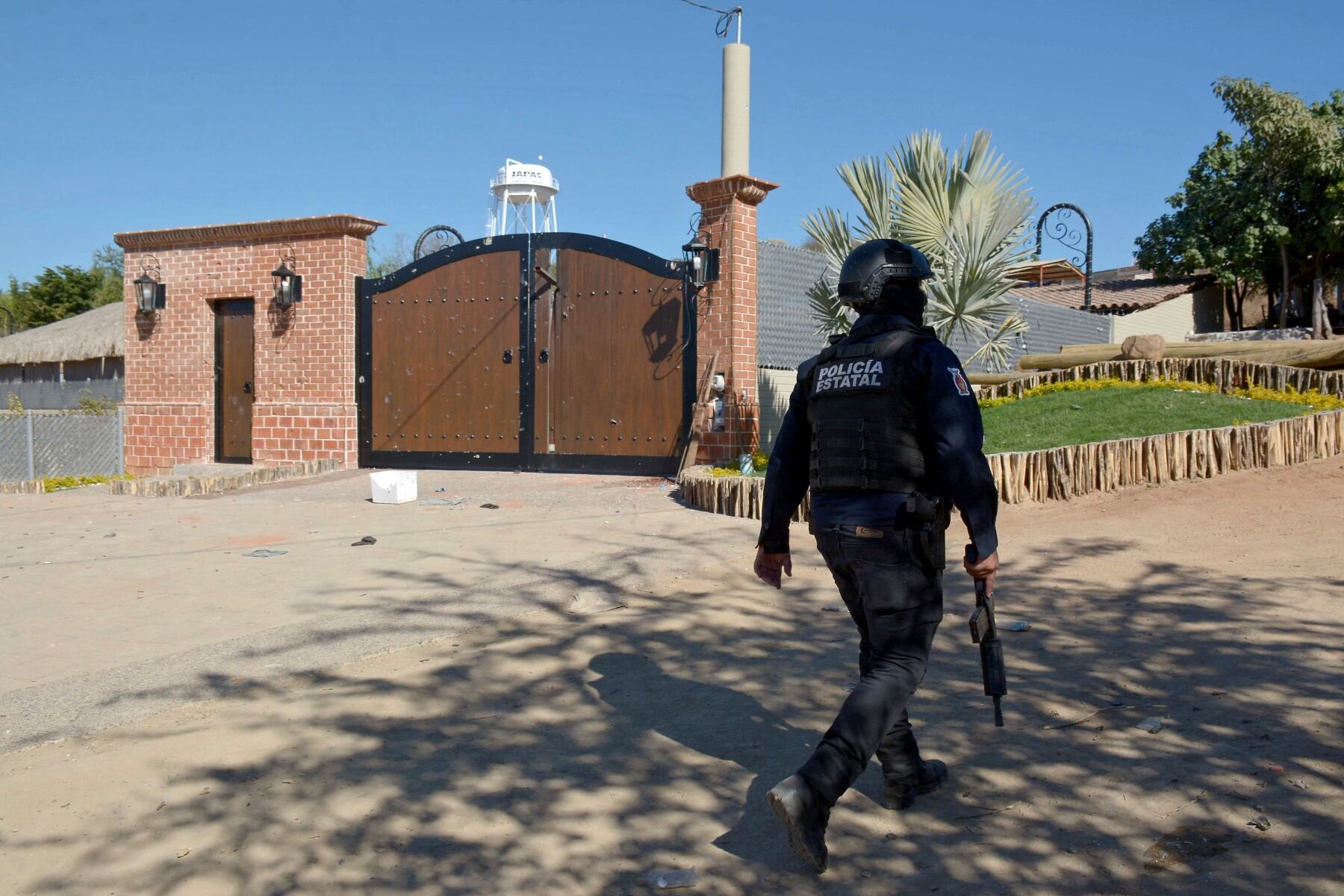A police officer walks outside the mansion where Ovidio Guzman, aka "El Raton" (The Mouse), son of jailed drug trafficker Joaquin "El Chapo" Guzman, was arrested on January 5, in the Jesus Maria area in Culiacan, Sinaloa State, Mexico, on January 7, 2023. Ten soldiers and 19 suspected criminals were killed in an operation to arrest Ovidio Guzman, with a dramatic shootout sowing terror at an airport. Thousands of soldiers retook control of the Sinaloa cartel stronghold of Culiacan, which resembled a war zone after furious gunmen went on the rampage to try to free their boss. Guzman was captured and flown to Mexico City before being transferred to the high-security Altiplano prison in central Mexico from which "El Chapo" once escaped. (Photo by JUAN CARLOS CRUZ / AFP)