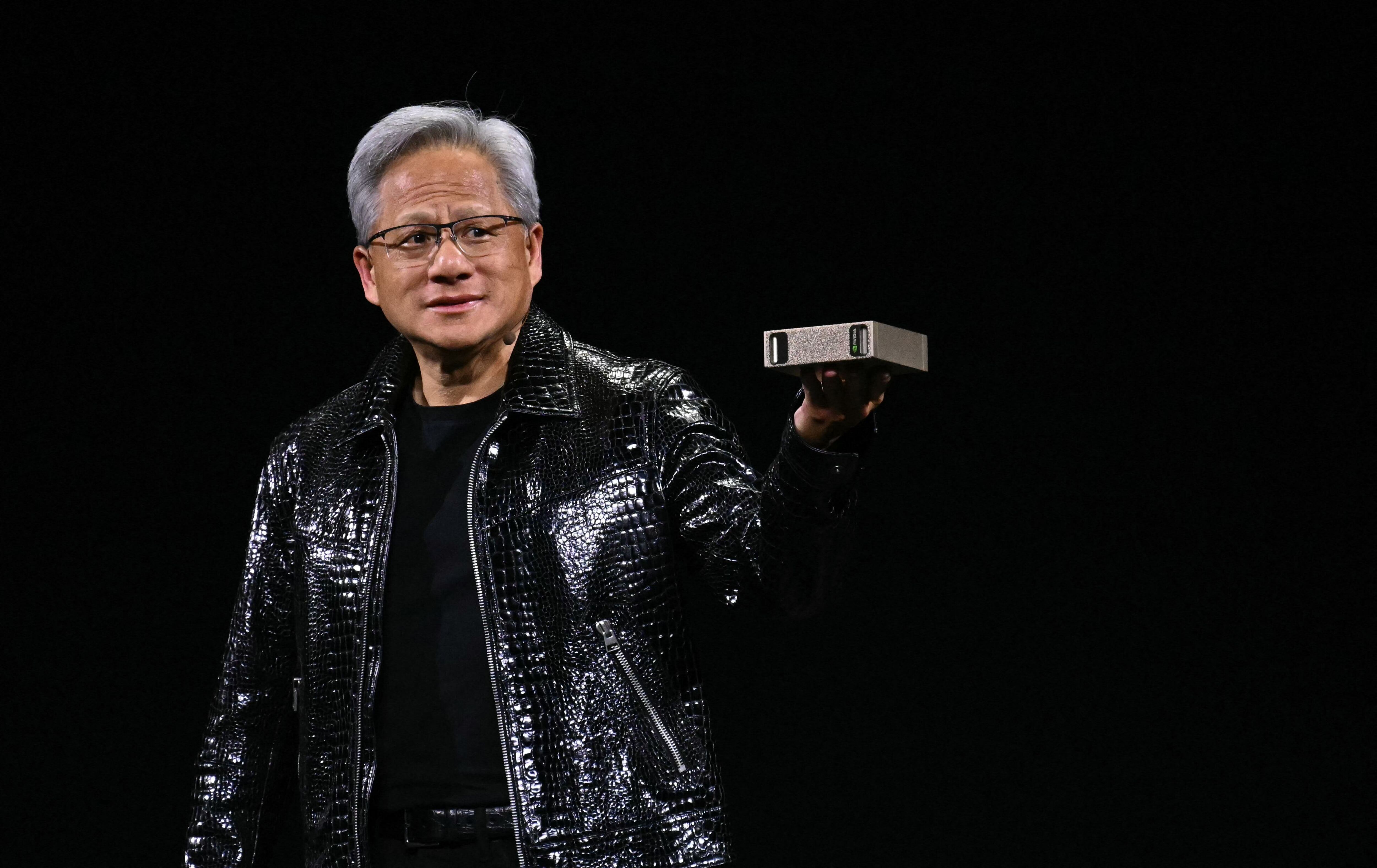 Jensen Huang, CEO de Nvidia, sosteniendo una computadora personal con inteligencia artificial durante su conferencia en el CES 2025 en Las Vegas, marcando un avance en el desarrollo de IA generativa para computadoras personales.
