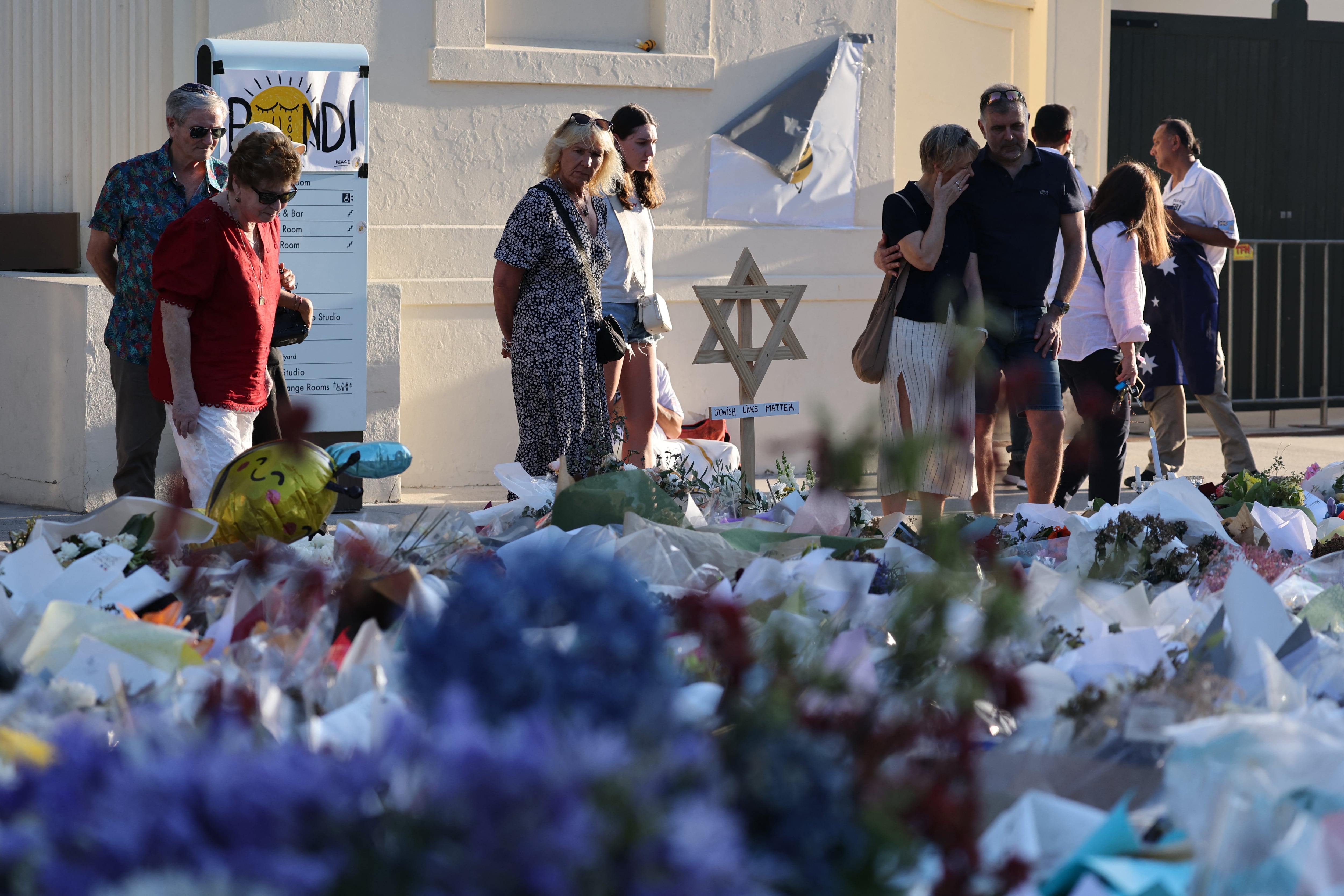 Los dolientes se reúnen frente a los homenajes depositados en memoria de las víctimas del tiroteo ocurrido en Bondi Beach, Sídney, el 20 de diciembre de 2025. Padre e hijo armados están acusados de disparar contra la multitud en un festival judío en la playa el 14 de diciembre, matando a 15 personas en un ataque que las autoridades vincularon con la ideología del Estado Islámico.