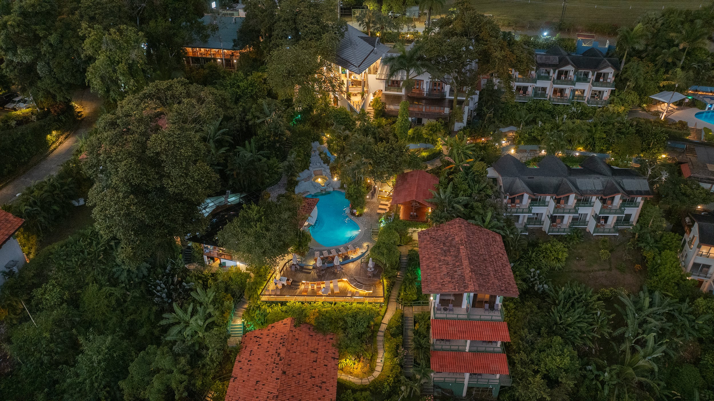 Resort & Wildlife Refuge Sí Como No, ubicado en Quepos rodeado de vegetación tropical con piscina iluminada, propiedad de Everty en Costa Rica.