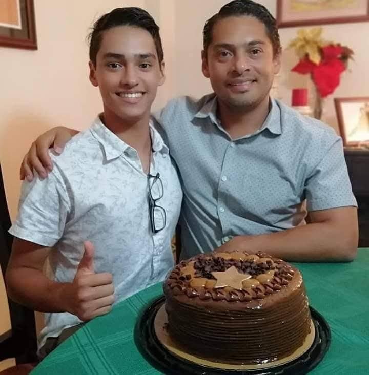 Un padre y su hijo abrazados, un pastel de cumpleaños al frente.