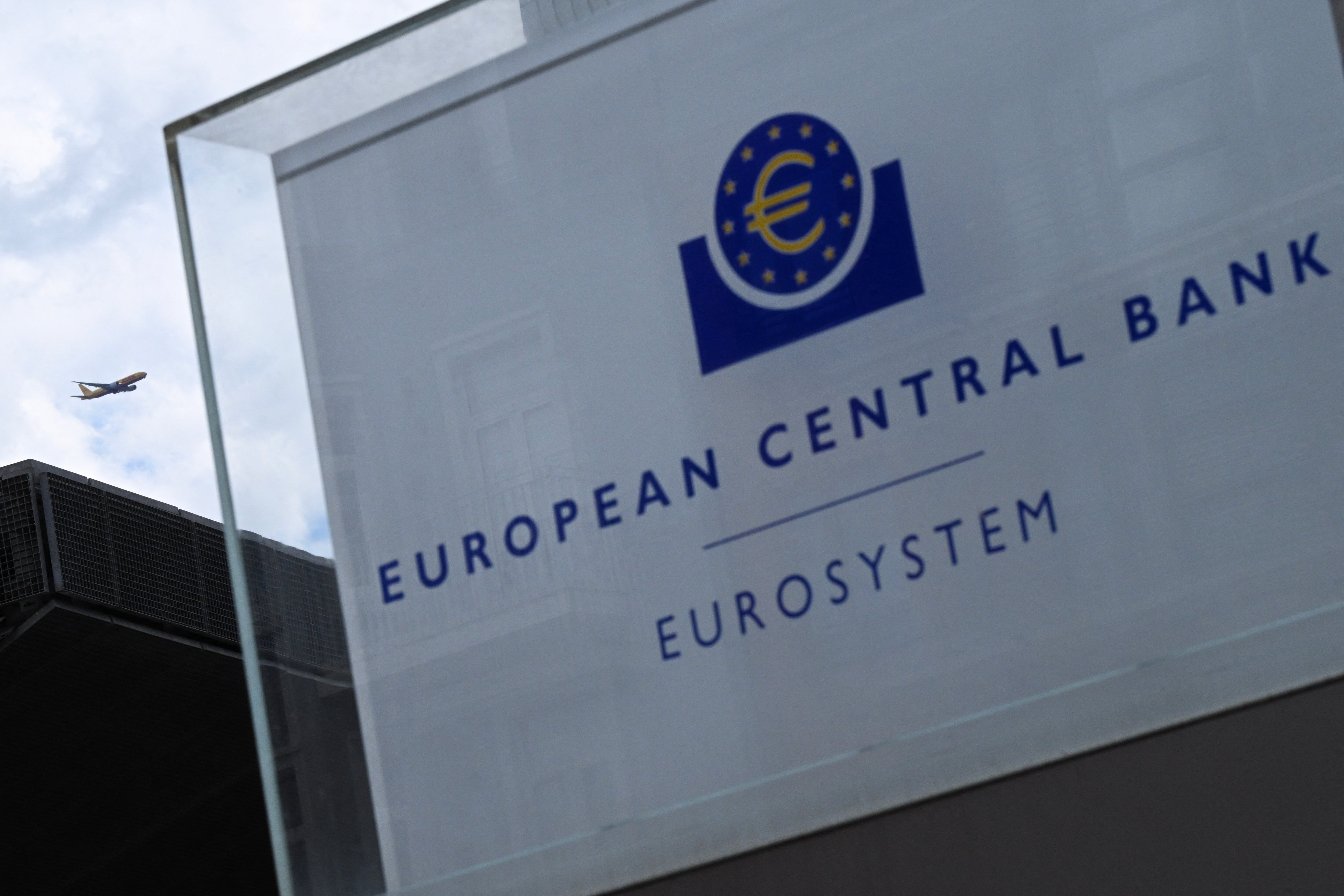 Primer plano del logo del Banco Central Europeo (BCE) en su edificio central en Frankfurt, con un avión volando en el cielo, destacando su papel en pruebas con la moneda digital CBDC.