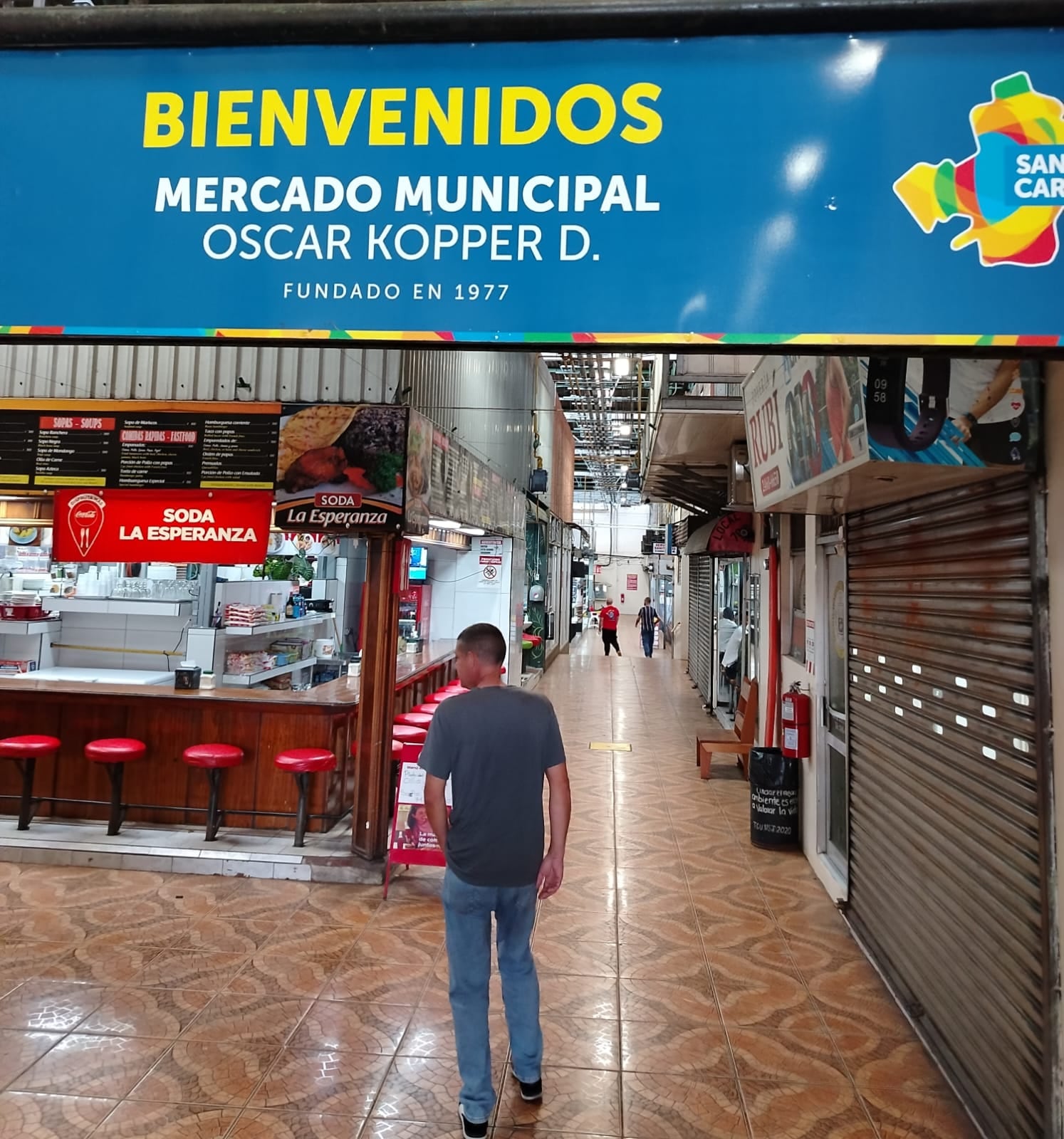 Pasillo interior del Mercado Municipal Óscar Kopper en Ciudad Quesada, San Carlos, con locales comerciales y una soda tradicional, espacio emblemático del comercio local fundado en 1977.