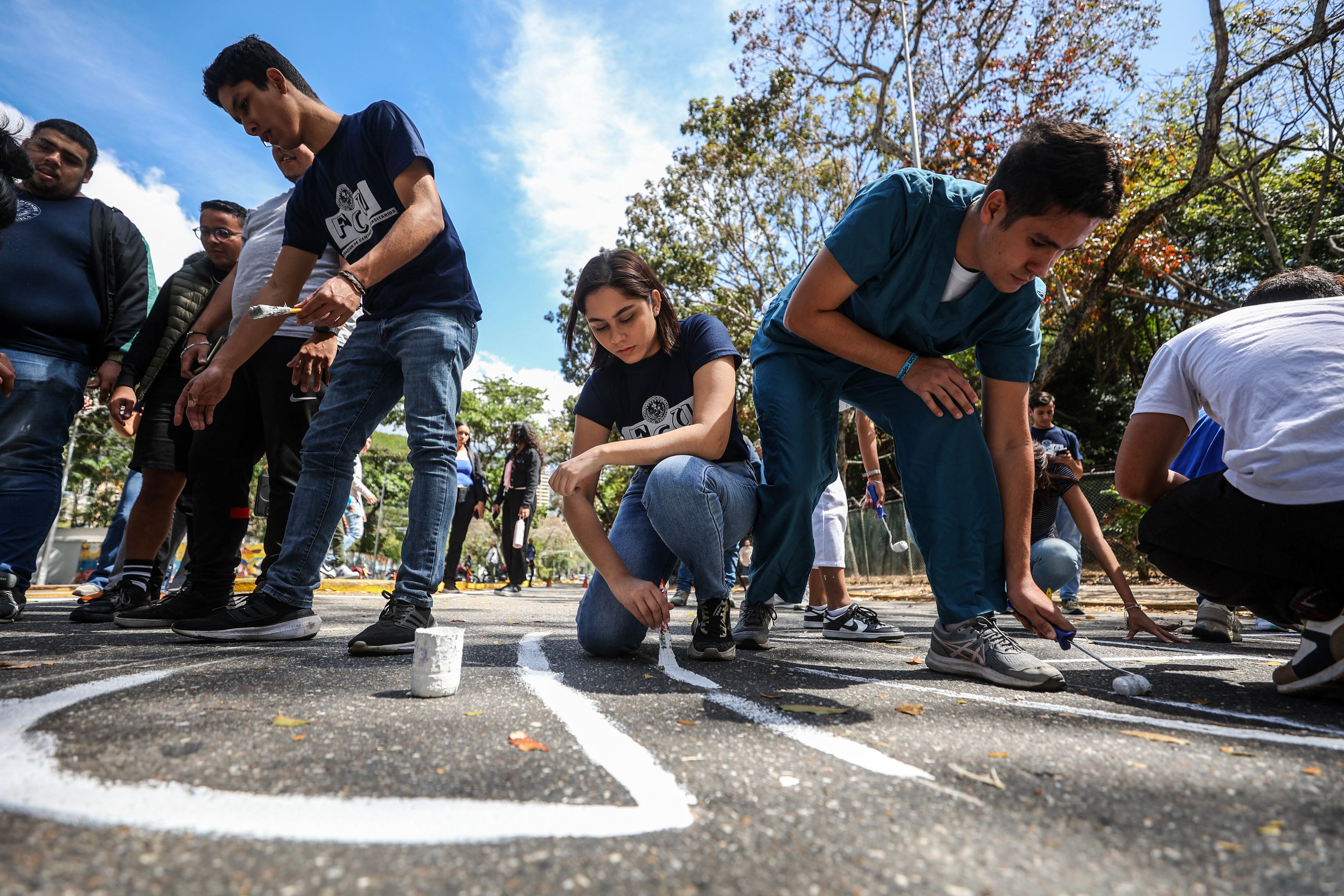 Students of the Central University of Venezuela paint names of missing students at the entrance of the university in celebration of the Venezuelan Youth Day in Caracas on February 12, 2025. (Photo by Pedro MATTEY / AFP)