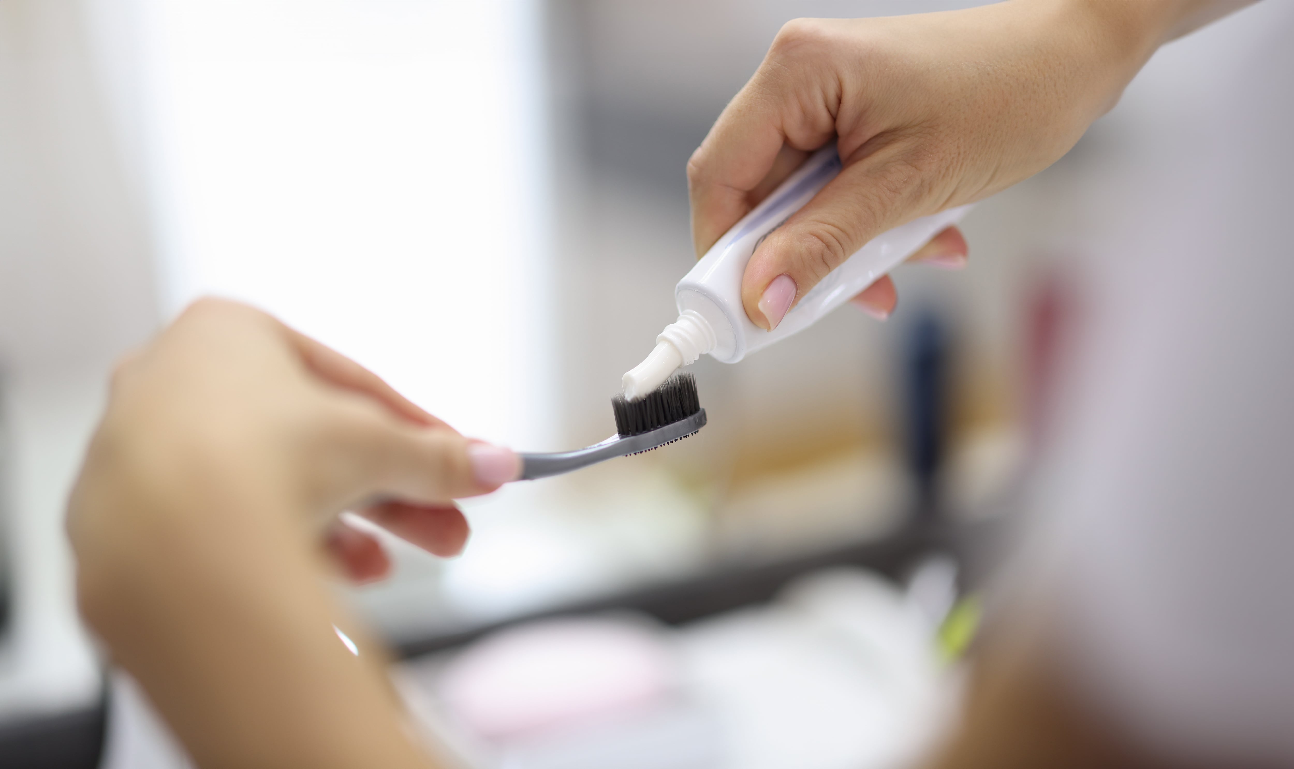 Manos de una mujer colocan pasta dental sobre un cepillo.