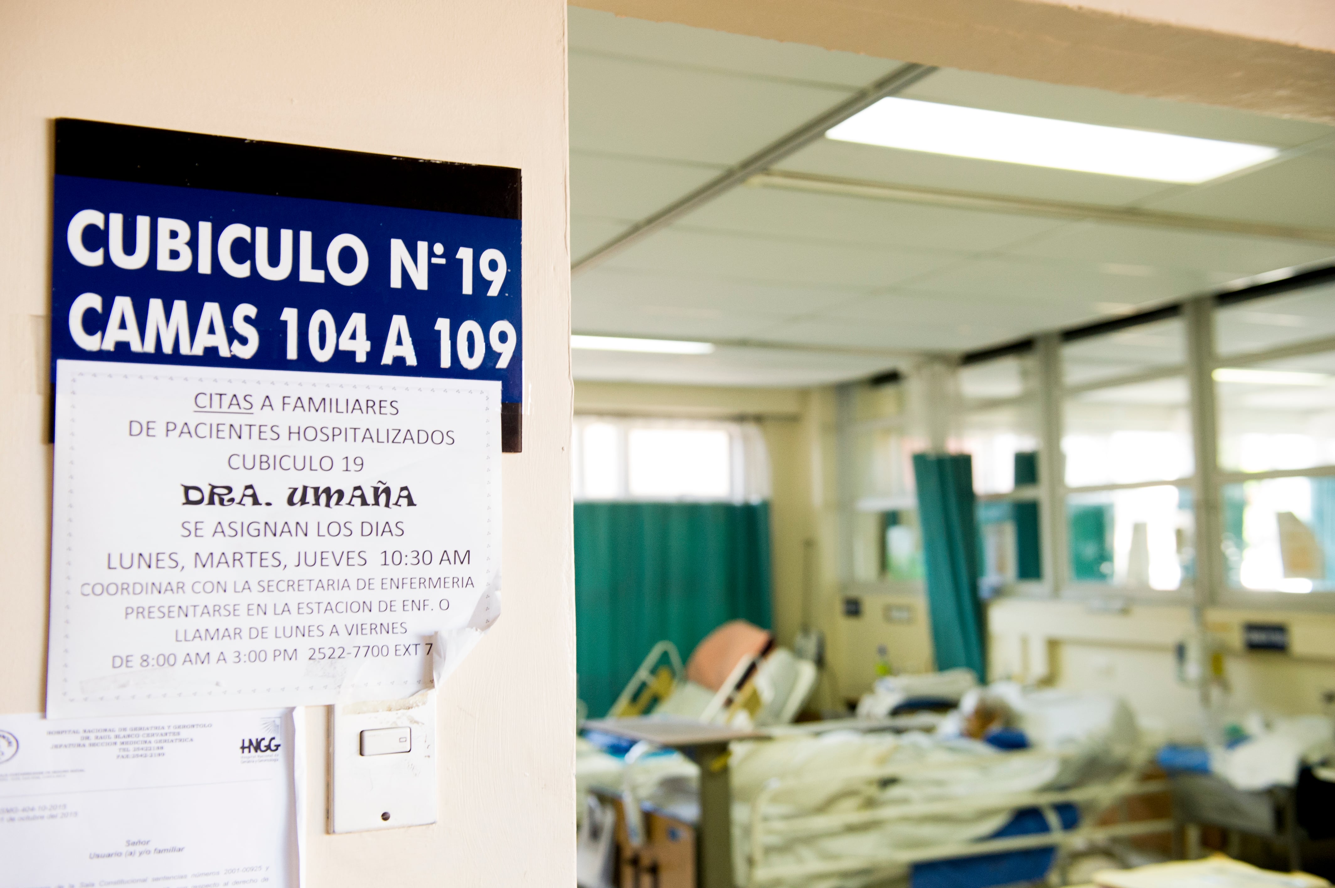 Entrada a un salón de hospital con camas de pacientes hospitalizados.