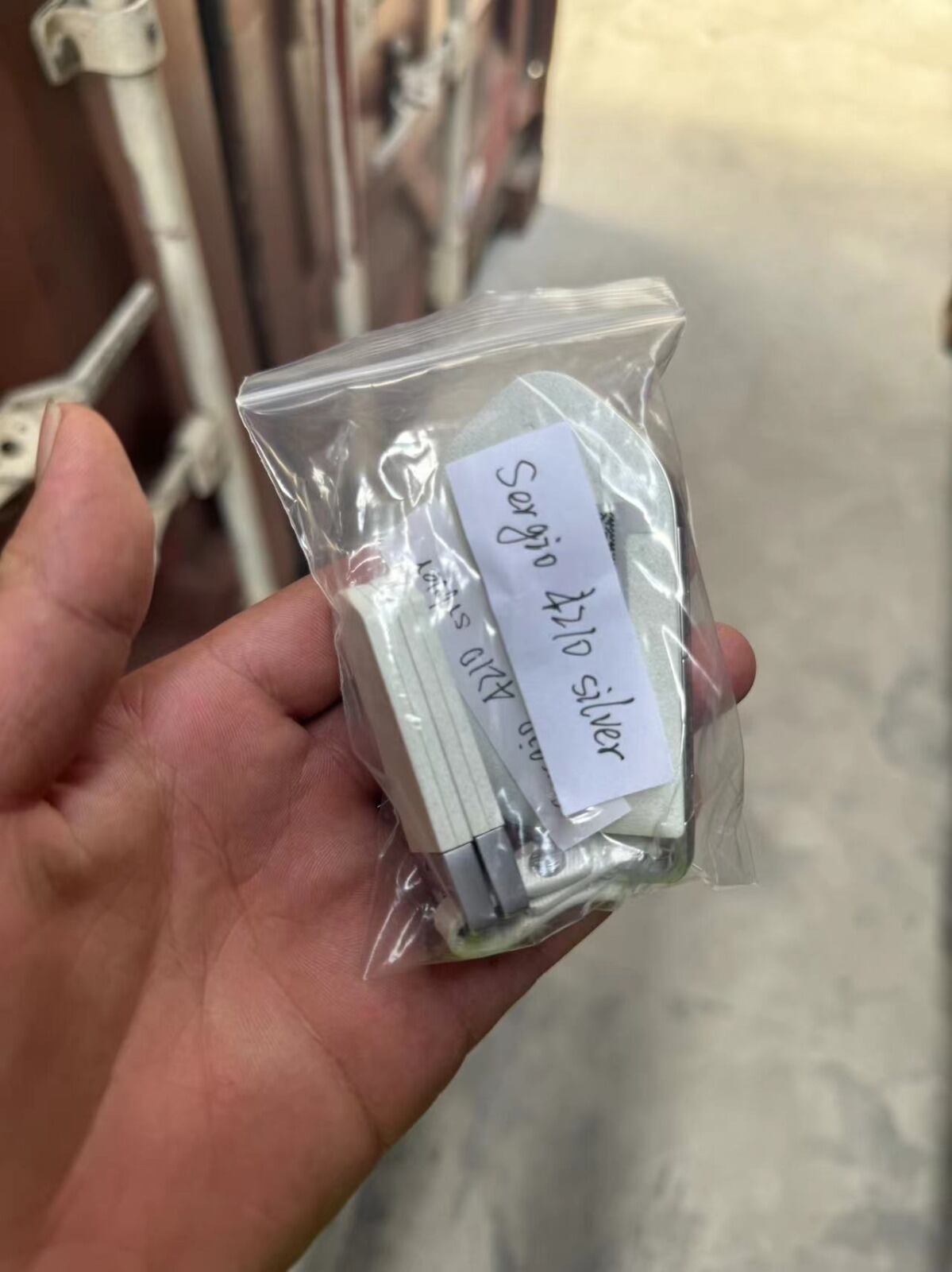 Llaves del vehículo modelo Kia dentro de una bolsa plástica transparente en un entorno industrial, listas para ser transportadas en un contenedor.